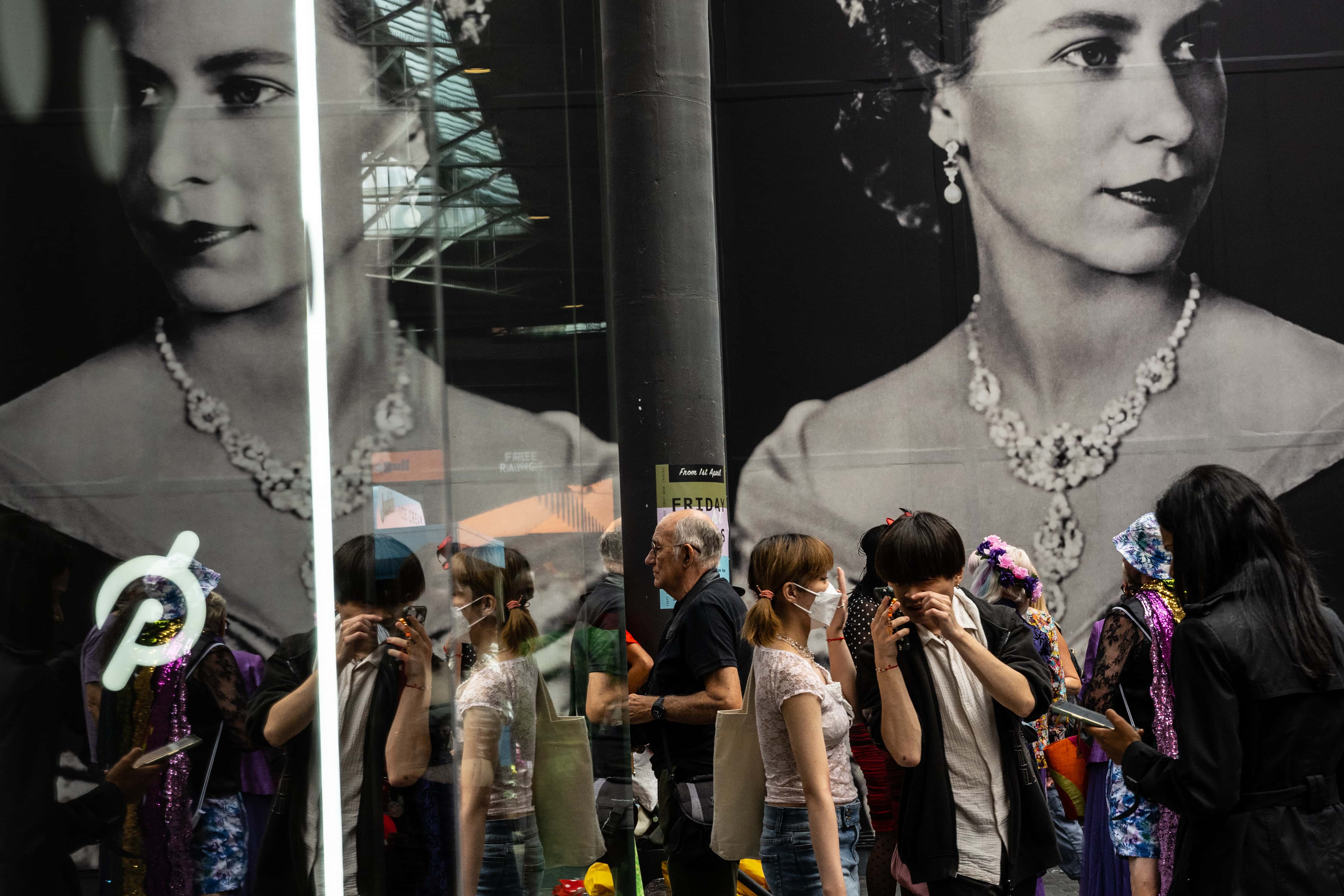 People walk past a picture of Britain's late Queen Elizabeth II in a Market on September 15, 2022 in London, England. Queen Elizabeth II is lying in state at Westminster Hall until the morning of her funeral to allow members of the public to pay their last respects. Elizabeth Alexandra Mary Windsor was born in Bruton Street, Mayfair, London on 21 April 1926. She married Prince Philip in 1947 and acceded to the throne of the United Kingdom and Commonwealth on 6 February 1952 after the death of her Father, King George VI. Queen Elizabeth II died at Balmoral Castle in Scotland on September 8, 2022, and is succeeded by her eldest son, King Charles III. (Photo by David Ramos/Getty Images)