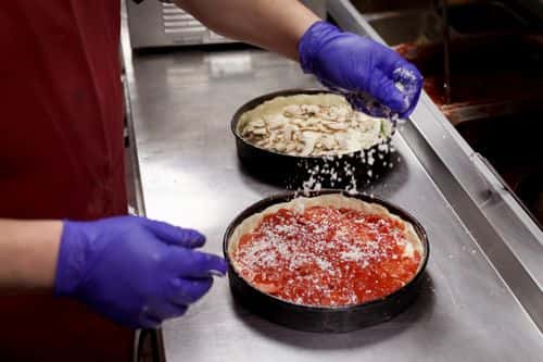 A worker prepares a Chicago-style deep dish pizza at a Lou Malnati's restaurant on March 31, 2022 in Chicago, Illinois. Restaurants, like the family-owned Lou Malnati's, have been hit by rising commodities prices such as wheat, which hit a record high after the start of the war in Ukraine.