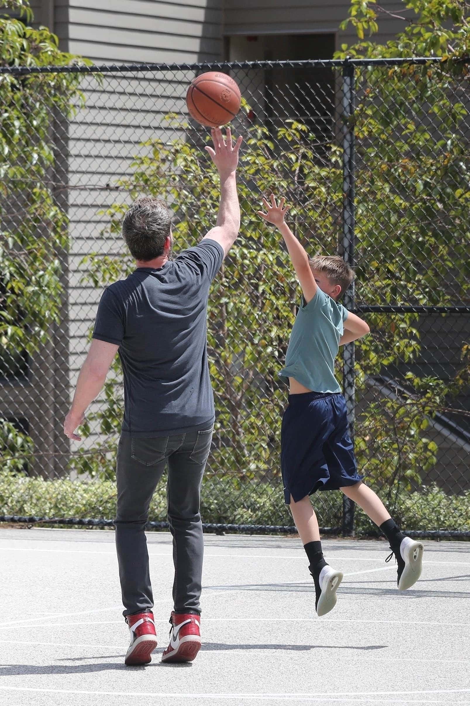 Affleck rocked a sporty look in a navy t-shirt that he paired with dark jeans and a pair of red, black, and white Nike sneakers. (Backgrid)