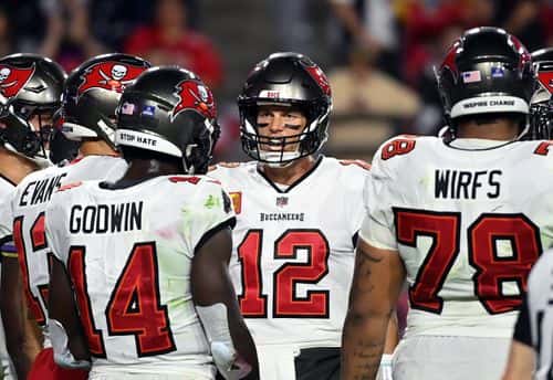 Tom Brady #12 of the Tampa Bay Buccaneers talks to teammates in the huddle during the 1st half of the game against the Arizona Cardinals at State Farm Stadium on December 25, 2022 in Glendale, Arizona.