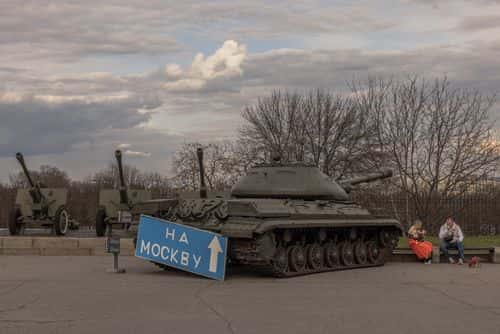 People sit on a bench next to a Soviet army tank with a board attached on it reading On Moscow at the National Museum of the History of Ukraine in the Second World War on March 27, 2023 in Kyiv, Ukraine. A war-time curfew in the capital city was moved back an hour from 11 p.m. to midnight beginning March 26.