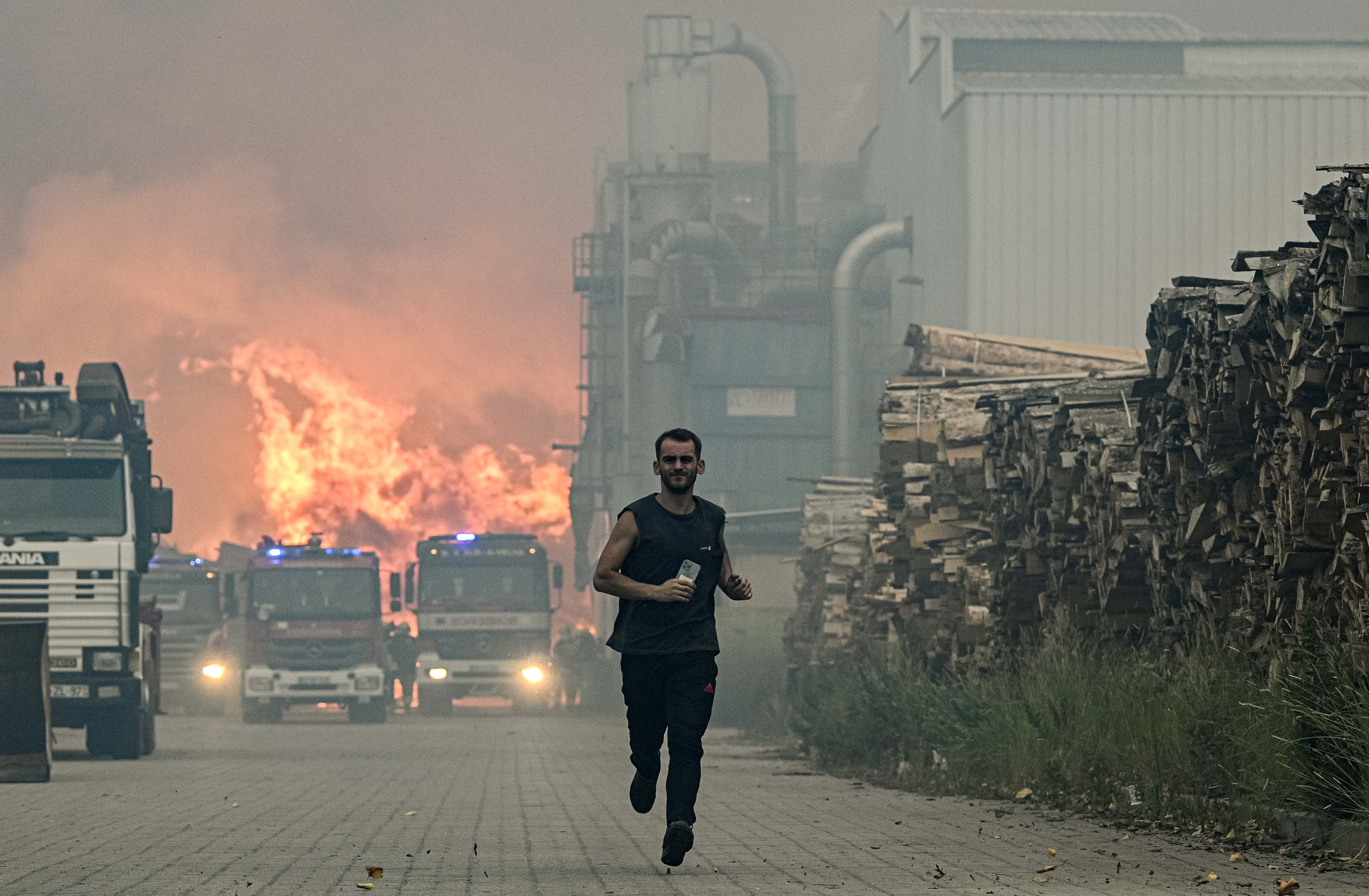 A worker runs away when a forest fire that has hit the lumber factory where he works on July 13, 2022 in Albergaria a Velha, Portugal. Wildfires have swept across the central part of the country amid temperatures exceeding 40 degrees celsius.