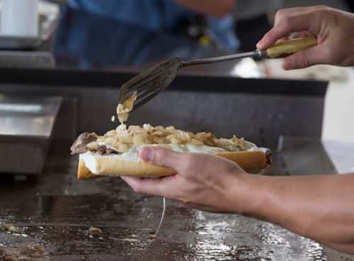 Juan Pablo Socino of the Newcastle Falcons makes a cheesesteak at Geno's Steaks on September 14, 2017 in Philadelphia, Pennsylvania.