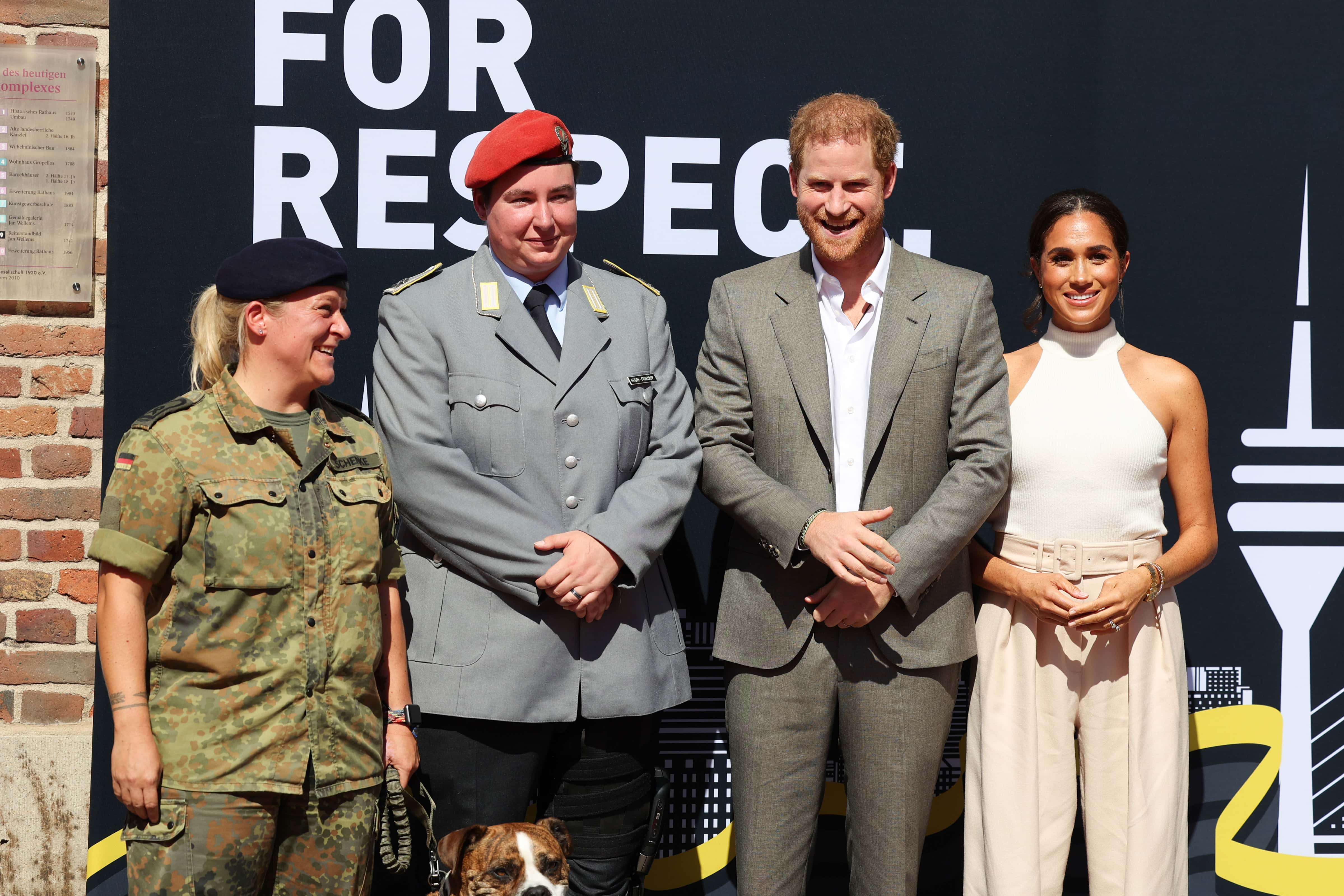 (L-R) Frau Hauptfeldwebel Steffi Schenke, Frau Hauptfeldwebel Lorraine Grosse-Fintrop, Prince Harry, Duke of Cambridge and Meghan, Duchess of Cambridge pose for a photo outside the town hall with the dog Loki during the Invictus Games Dusseldorf 2023 - One Year To Go events on September 06, 2022 in Dusseldorf, Germany. The Invictus Games will be held in Germany for the first time in September 2023. (Photo by Mathis Wienand/Getty Images)