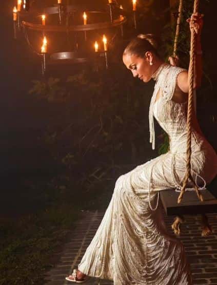 Lopez taking a swing in her third wedding gown with pearl strings (Screenshot via OnTheJLO.com)