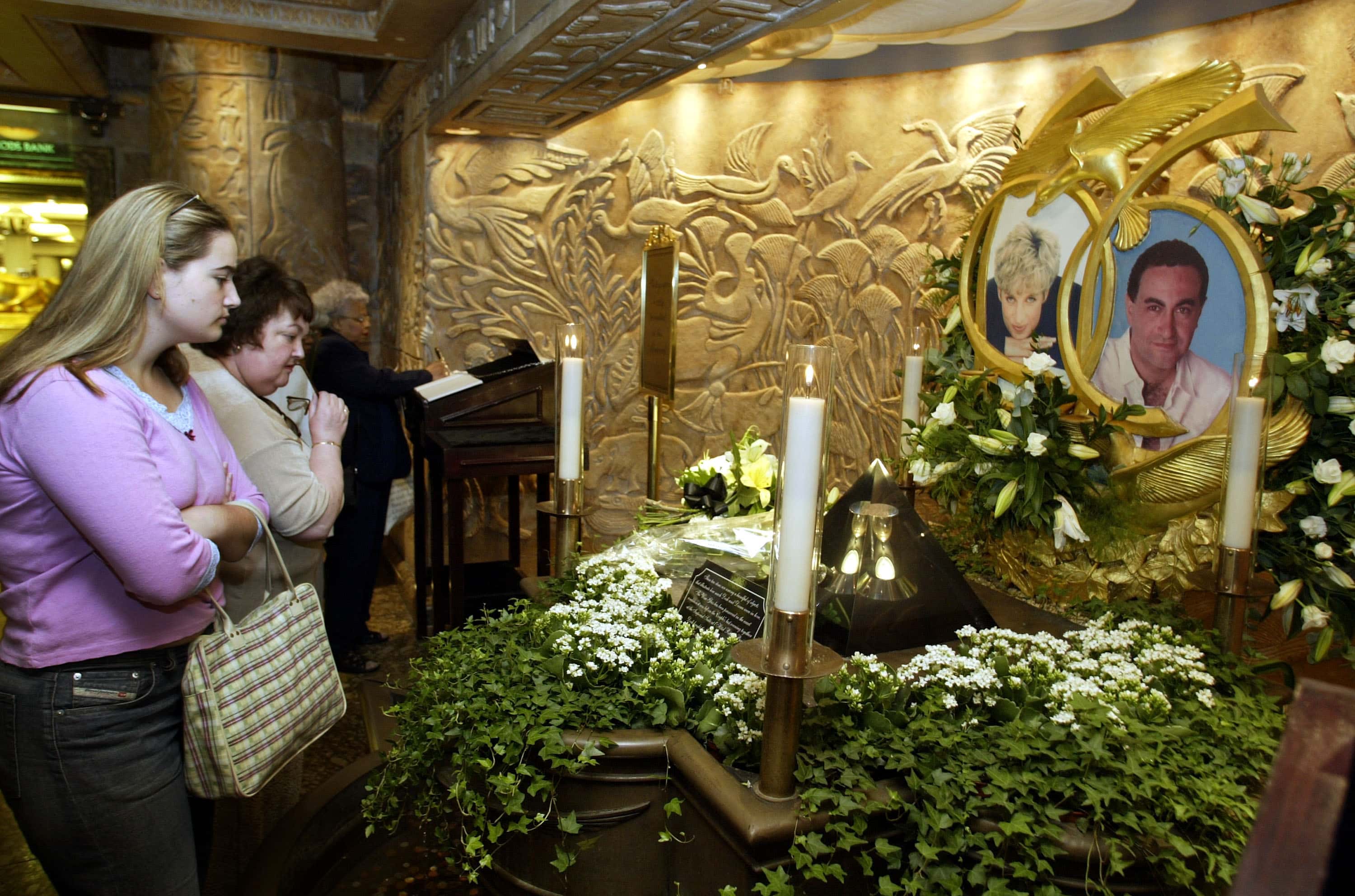 People look at the memorial to Diana, Princess of Wales and Dodi Al Fayed in Harrods department store August 31, 2002 in London, England. Princess Diana, 36-years-old, died with her companion Dodi Fayed, 41-years-old, in a car crash August 31, 1997 in Paris, France. Fayed was the son of an Egyptian billionaire. (Photo by Scott Barbour/Getty Images)