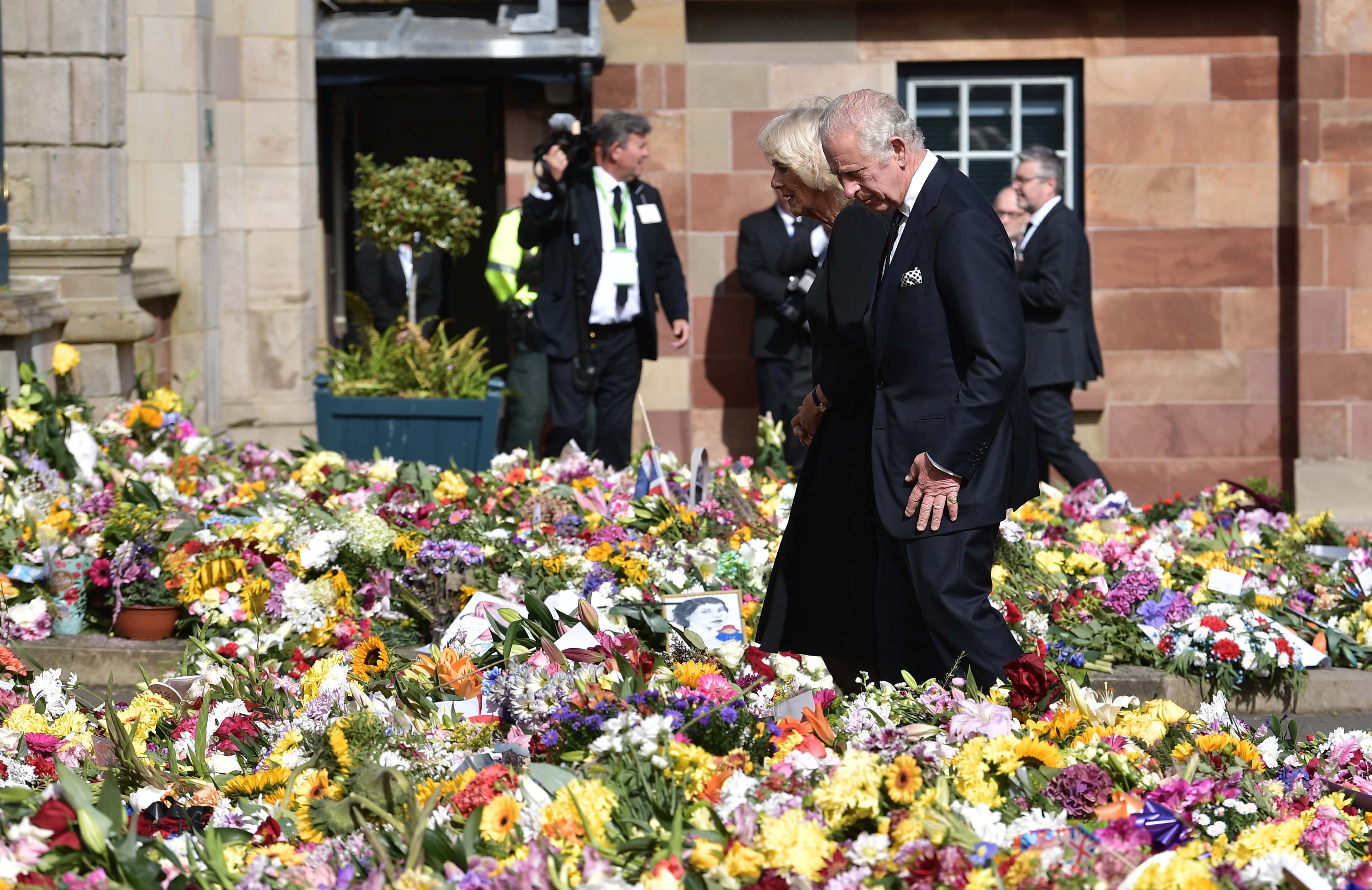 His Majesty King Charles III accompanied by Camilla, Queen Consort inspects the floral tributes left for his late mother Her Majesty Queen Elizabeth II outside Hillsborough Castle on September 13, 2022 in Hillsborough, Northern Ireland. King Charles III is visiting Northern Ireland for the first time since ascending to the throne following the death of his mother, Queen Elizabeth II, who died at Balmoral Castle on September 8, 2022. (Photo by Charles McQuillan/Getty Images)