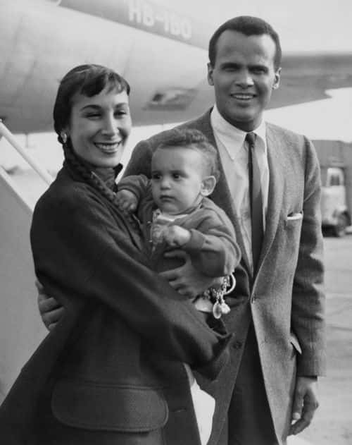 American dancer Julie Belafonte holding her son, David, with husband, American singer-songwriter and civil rights activist Harry Belafonte at an unspecified airport in London, England, 31st July 1958. Harry Belafonte is in London to perform a series of shows. (Photo by Express/Archive Photos/Hulton Archive/Getty Images)