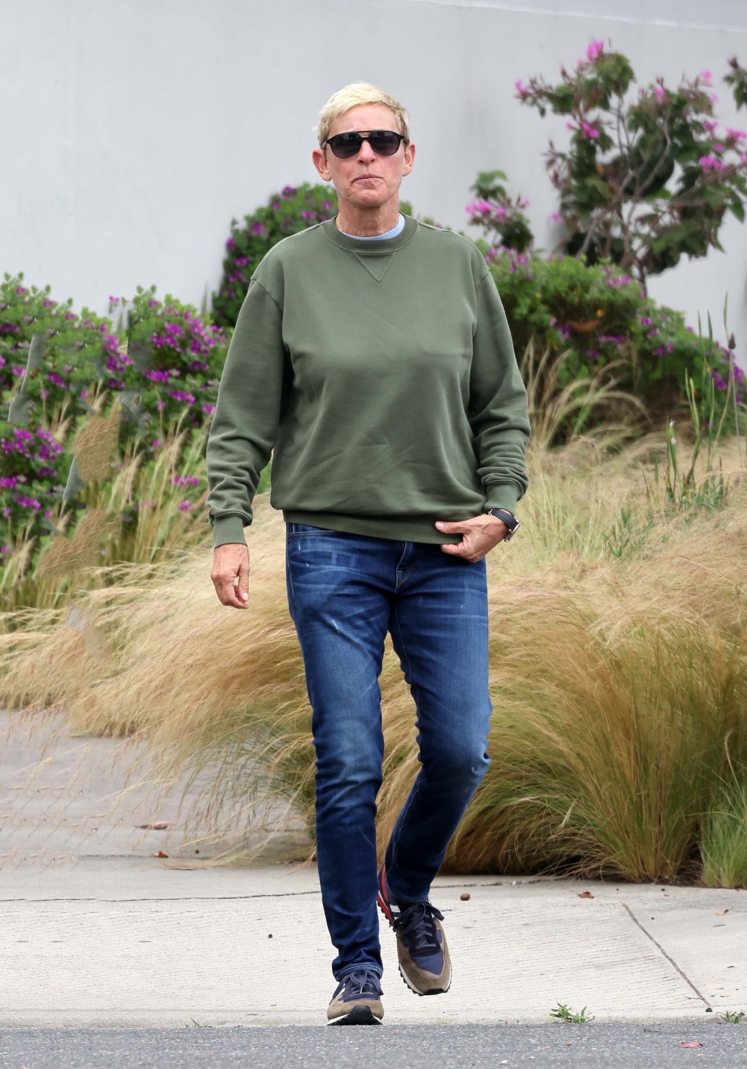 Sporting a sage green crew neck sweatshirt, denim blue jeans, and brown sneakers, the ever-stylish Ellen, 65, added a touch of flair with black sunglasses and a sleek wristwatch (Backgrid)