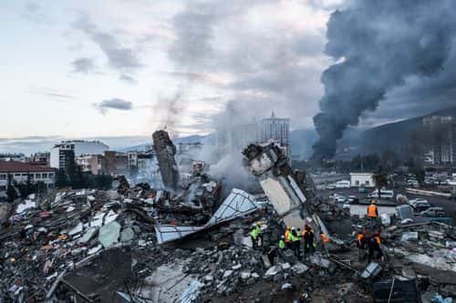 Smoke billows from the Iskenderun Port as rescue workers work at the scene of a collapsed building on February 07, 2023 in Iskenderun, Turkey. A 7.8-magnitude earthquake hit near Gaziantep, Turkey, in the early hours of Monday, followed by another 7.5-magnitude tremor just after midday. The quakes caused widespread destruction in southern Turkey and northern Syria and were felt in nearby countries.