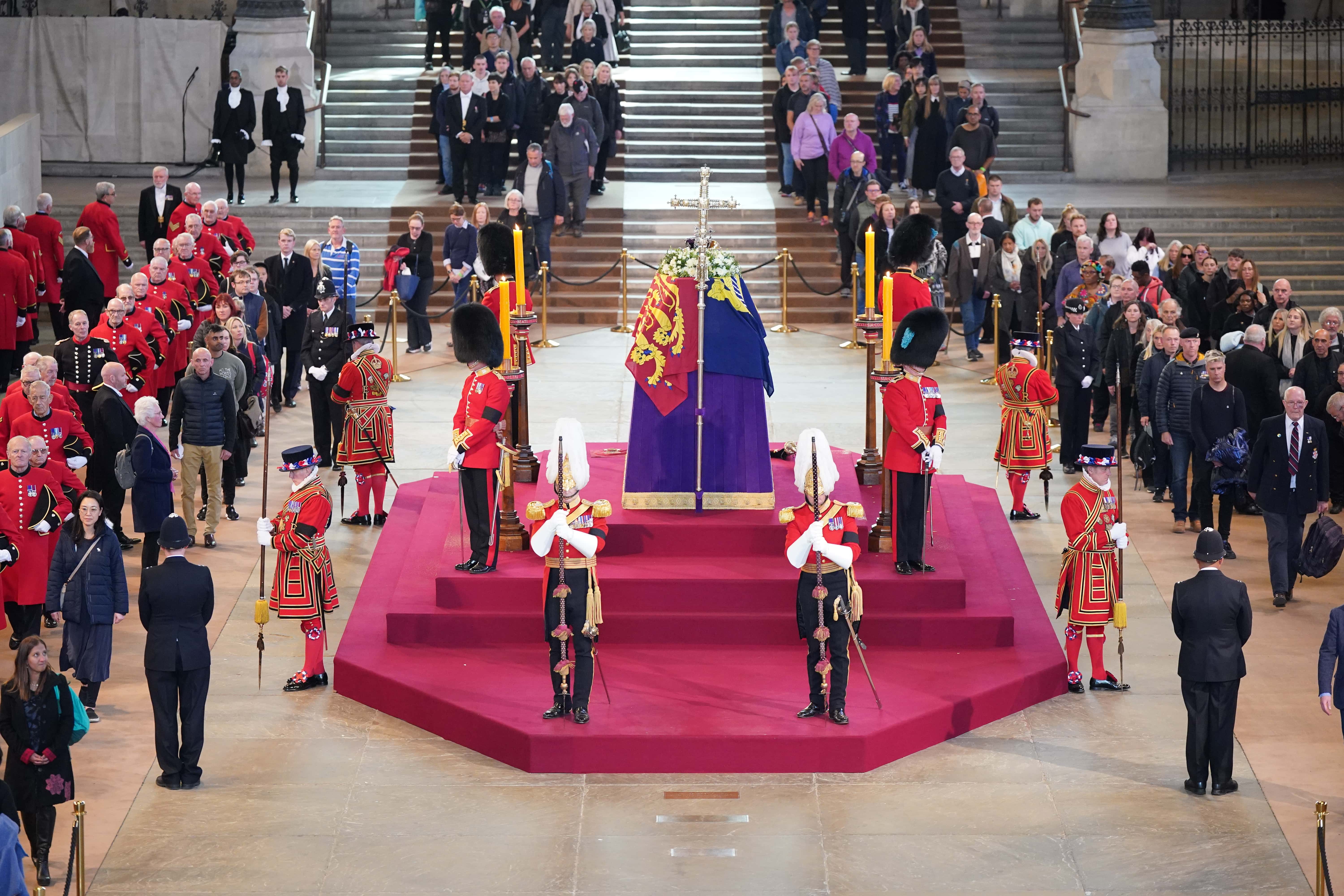 Chelsea Pensioners join members of the public as they file past the coffin of Queen Elizabeth II, draped in the Royal Standard with the Imperial State Crown and the Sovereign's orb and sceptre, lying in state on the catafalque in Westminster Hall, at the Palace of Westminster, ahead of her funeral on Monday, on September 16, 2022 in London, England. Members of the public are able to pay respects to Her Majesty Queen Elizabeth II for 23 hours a day until 06:30 on September 19, 2022. Queen Elizabeth II died at Balmoral Castle in Scotland on September 8, 2022, and is succeeded by her eldest son, King Charles III. (Photo by Yui Mok - WPA Pool/Getty Images)