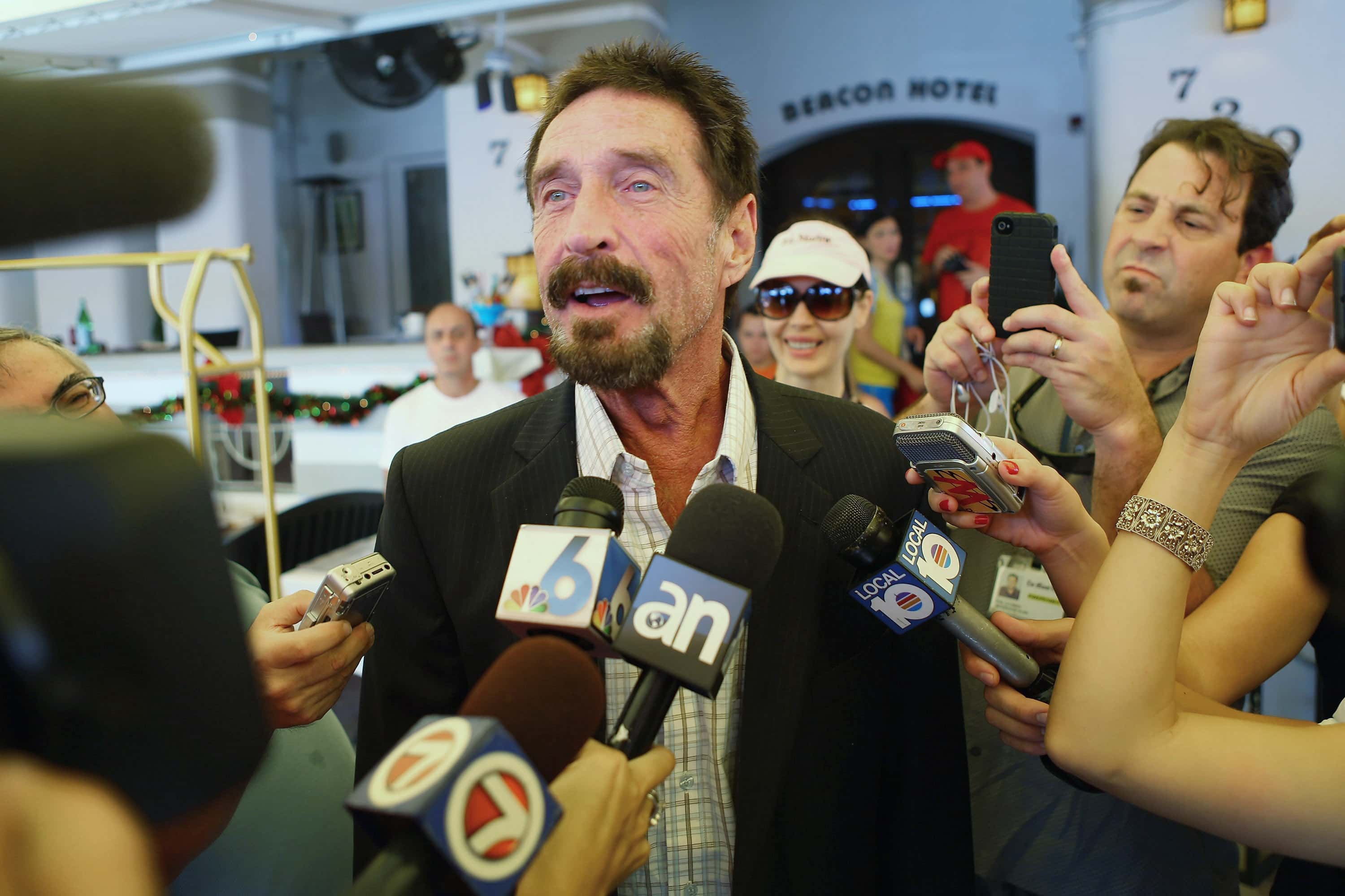 John McAfee talks to the media outside Beacon Hotel where he is staying after arriving last night from Guatemala on December 13, 2012 in Miami Beach, Florida. McAfee is a