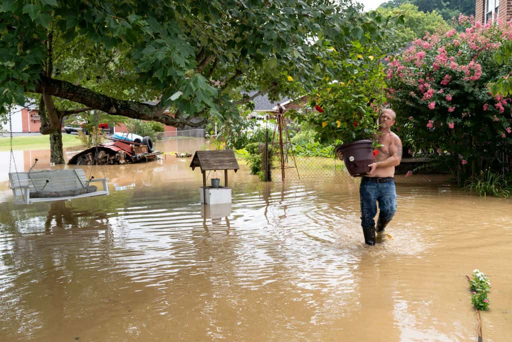 Cristopher Howard carries plants from his garden on July 28, 2022 in downtown Jackson, Kentucky, where the flooding is not expected to reach its peak until 9 P.M. this evening. (Photo by Michael Swensen/Getty Images)