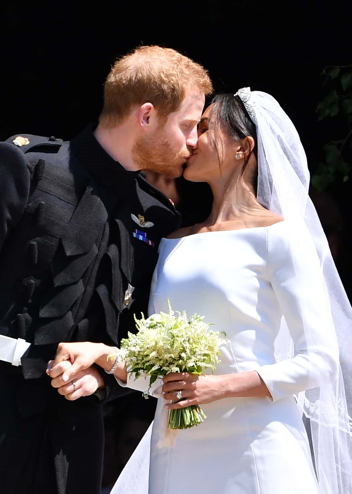 Britain's Prince Harry, Duke of Sussex kisses his wife Meghan, Duchess of Sussex as they leave from the West Door of St George's Chapel, Windsor Castle, in Windsor on May 19, 2018 in Windsor, England.