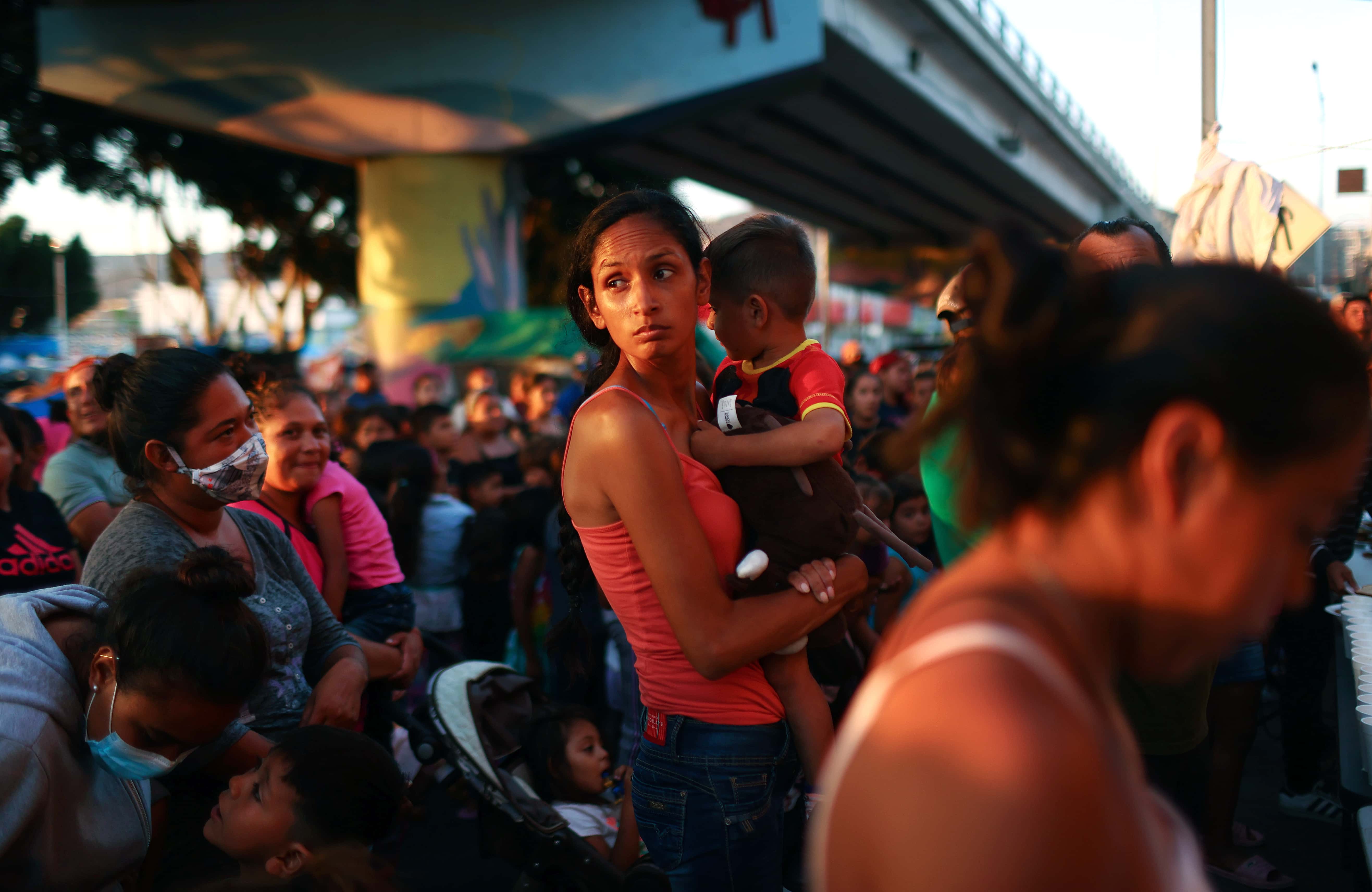 Asylum-seeking migrant Blanca holds her son Claudio as migrants await meals donated by a church group at a makeshift camp on the Mexican side of the San Ysidro Port of Entry on July 20, 2021 in Tijuana, Mexico. Around 2,000 migrants are waiting at the camp for the opportunity to apply for asylum in the United States as the Biden administration has haltingly restarted the asylum system along the southwest border, temporarily allowing in a few hundred people per day who are deemed the most vulnerable.
