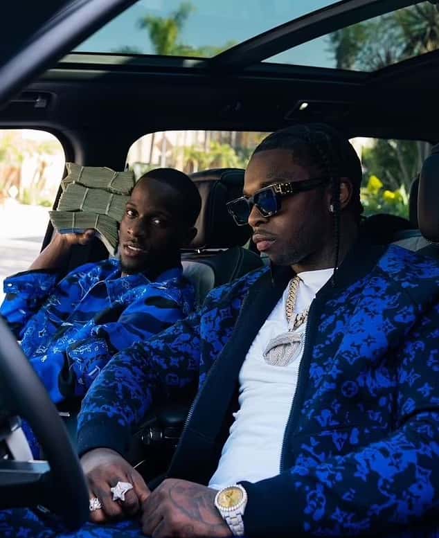 In another photo, Pop Smoke is sitting in the driver's seat of the SUV next to his friend Mike Dee, who is holding a massive stack of cash (Instagram)