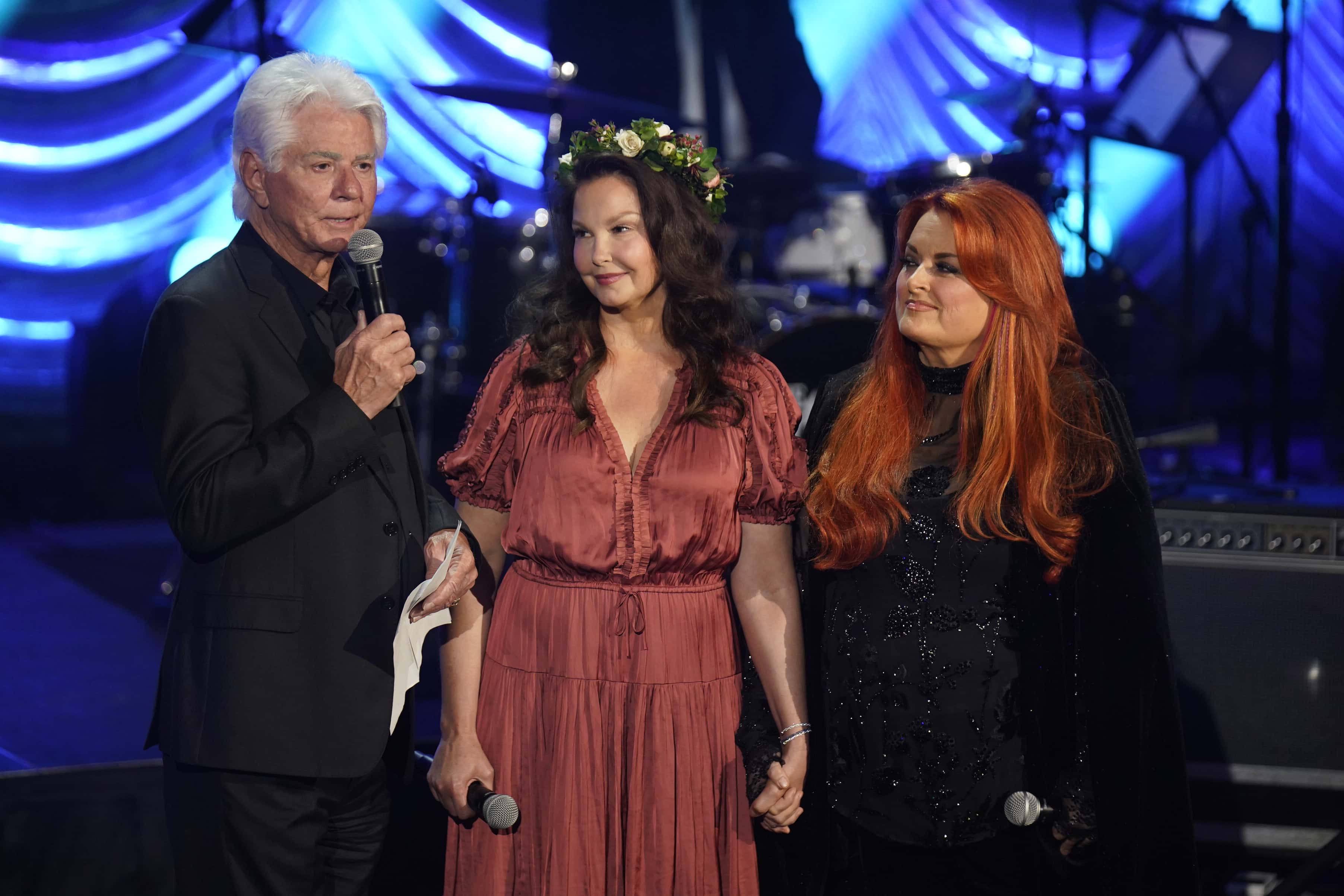 (L-R) Larry Strickland, Ashley Judd, and Wynonna Judd speak onstage for Naomi Judd: 'A River Of Time' Celebration at Ryman Auditorium on May 15, 2022 in Nashville, Tennessee.