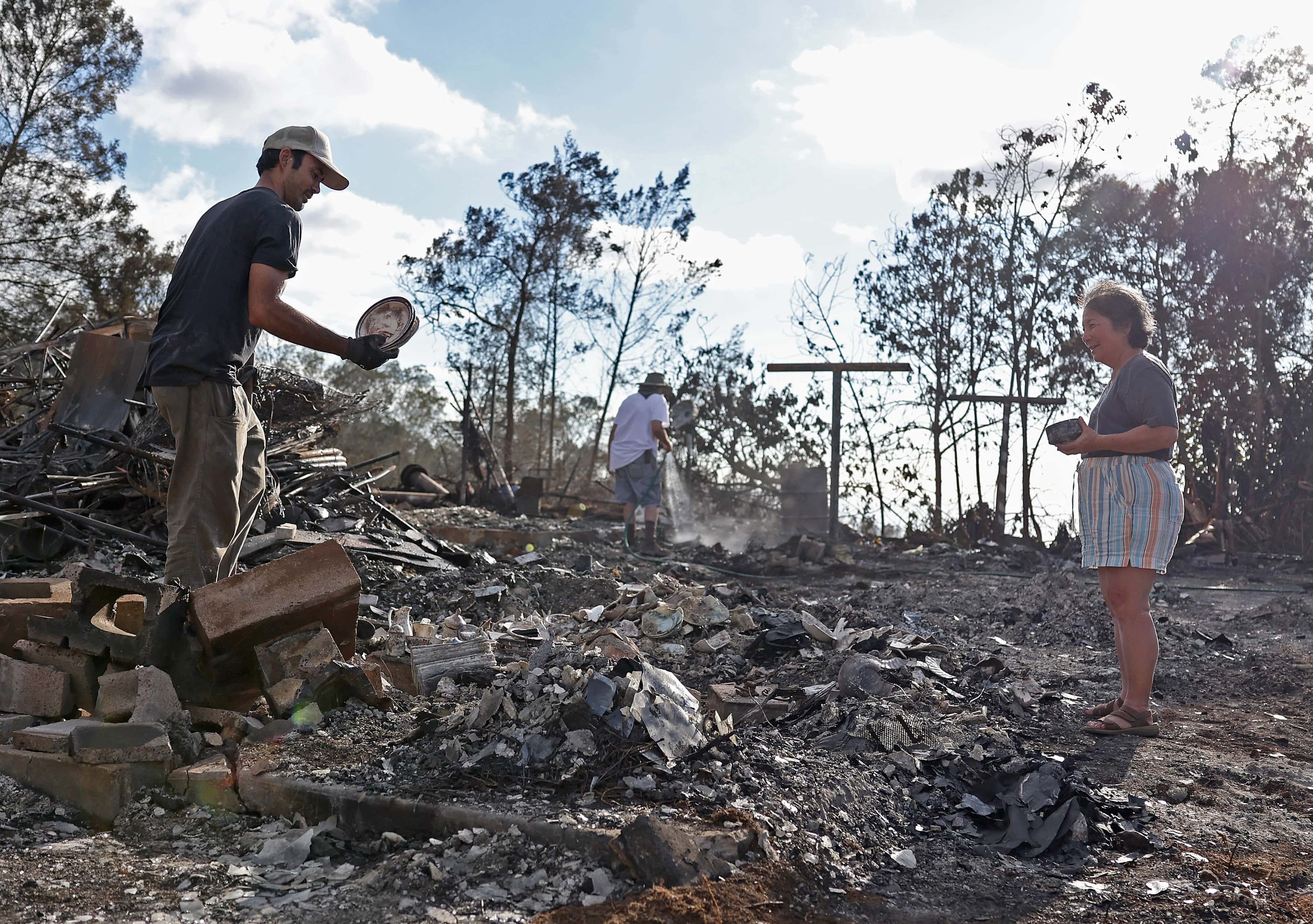 KULA, HAWAII - AUGUST 12: Brook Cretton (L) holds a stack of dishes that he salvaged from the rubble of a home that was destroyed by wildfire on August 12, 2023 in Kula, Hawaii. At least 80 people were killed and thousands were displaced after a wind-driven wildfire devastated the towns of Lahaina and Kula on Tuesday. Crews are continuing to search for missing people. (Photo by Justin Sullivan/Getty Images)