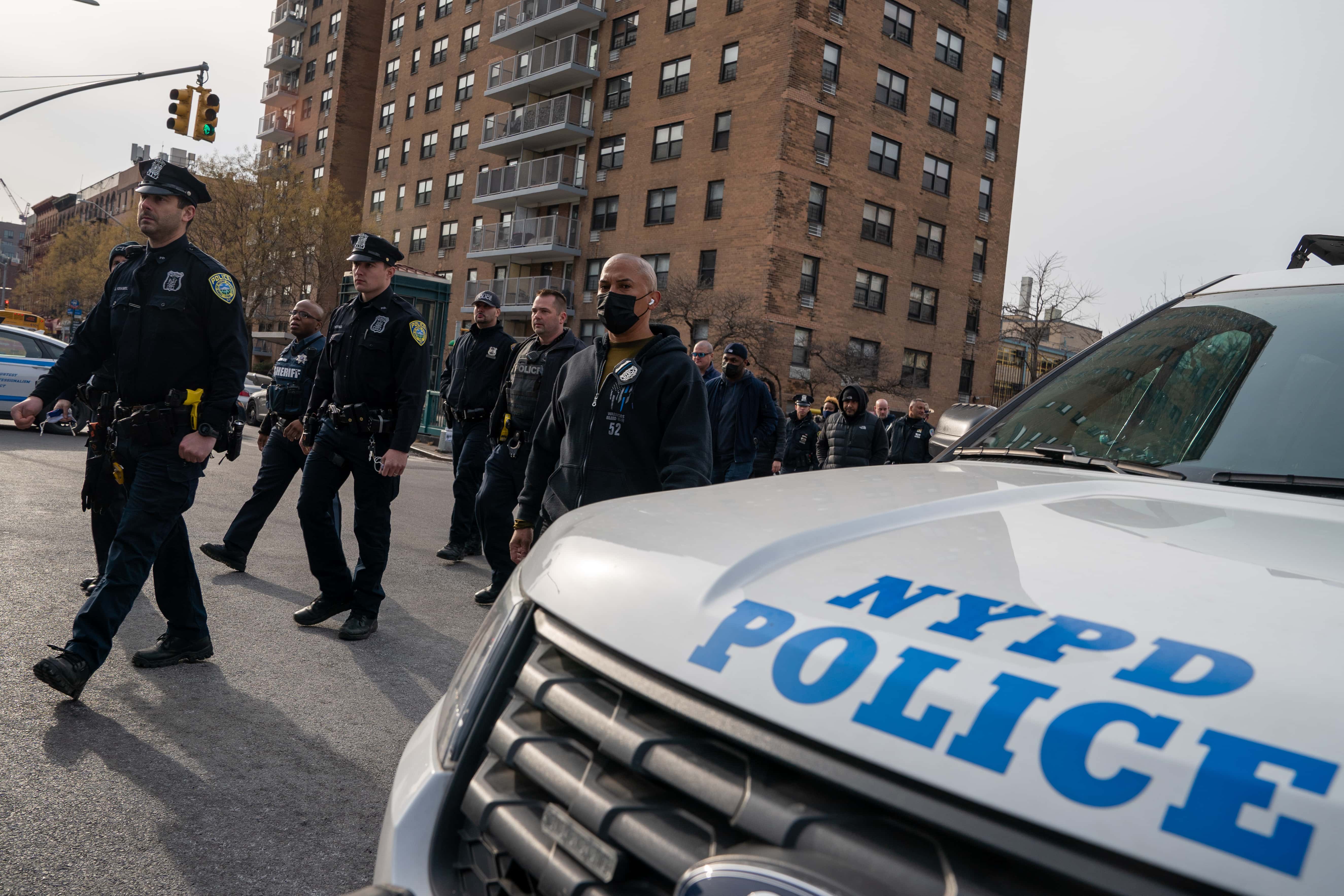 Police officers walk from the NYPD 32nd Precinct to Harlem Hospital near the scene where two officers where gunned down on January 23, 2022 in New York City. Officer Jason Rivera was killed in the attack. Officer Wilbert Mora was wounded and remains hospitalized.