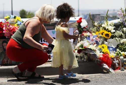 Jessica (L) and Kalani Windham leave flowers and a candle outside Walmart, near the scene of a mass shooting which left at least 20 people dead, on August 4, 2019 in El Paso, Texas. A 21-year-old male suspect, identified as Patrick Crusius from a Dallas suburb, surrendered to police at the scene. At least 26 people were wounded in the shooting.