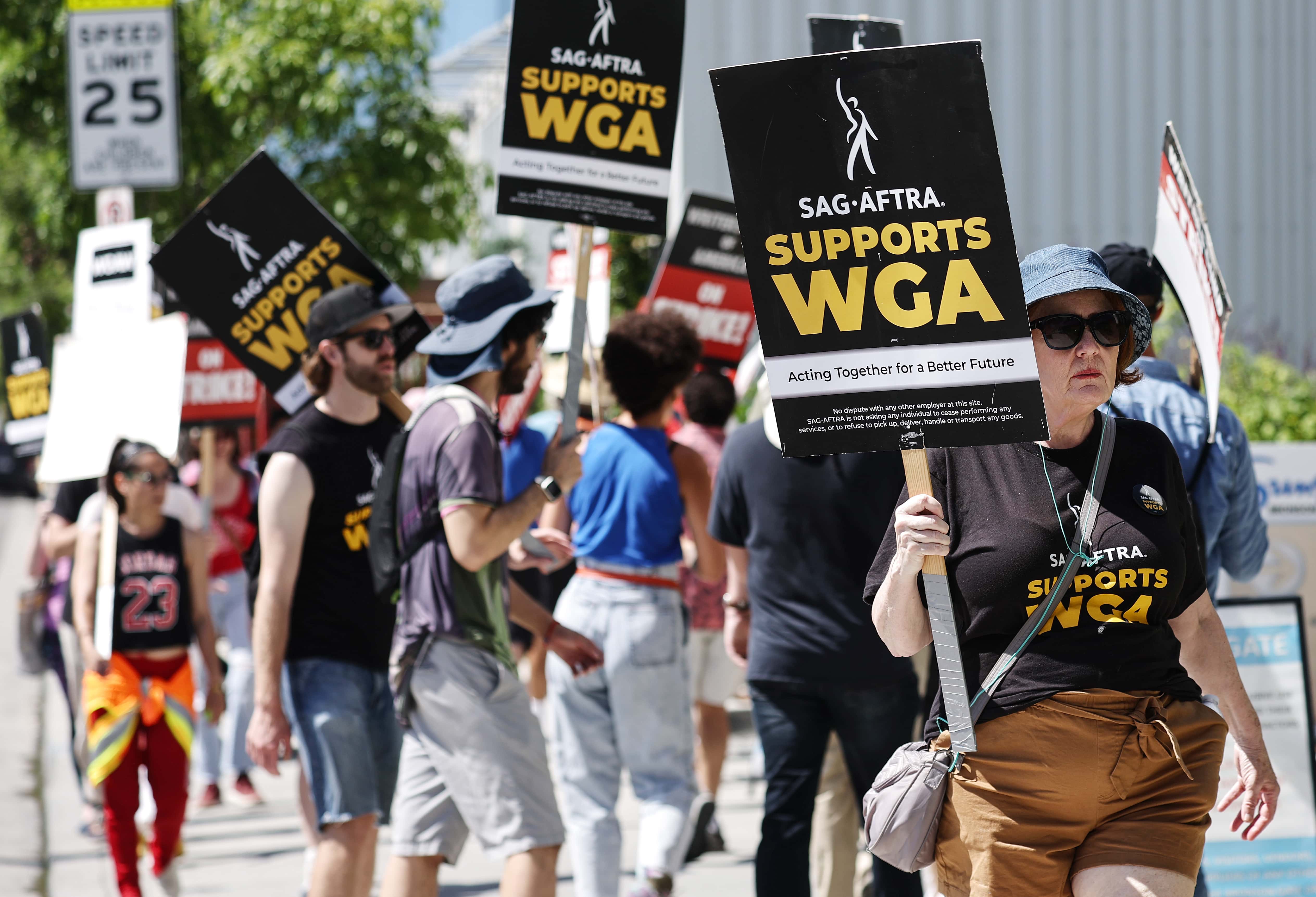 LOS ANGELES, CALIFORNIA - JULY 11: Signs read 'SAG-AFTRA Supports WGA' as SAG-AFTRA members walk the picket line in solidarity with striking WGA (Writers Guild of America) workers outside Netflix offices on July 11, 2023 in Los Angeles, California. Industry insiders concerned about the possibility of a potential actors’ strike will have to wait a little bit longer to know for sure. SAG-AFTRA and top studios and streamers have agreed to extend their current contract negotiations until July 12 at 11:59 p.m. (Photo by Mario Tama/Getty Images)