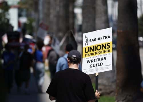 A sign reads 'Unions Stand Together' as SAG-AFTRA members walk the picket line in solidarity with striking WGA (Writers Guild of America) workers outside Netflix offices on July 11, 2023 in Los Angeles, California. Industry insiders concerned about the possibility of a potential actors’ strike will have to wait a little bit longer to know for sure. SAG-AFTRA and top studios and streamers have agreed to extend their current contract negotiations until July 12 at 11:59 p.m.