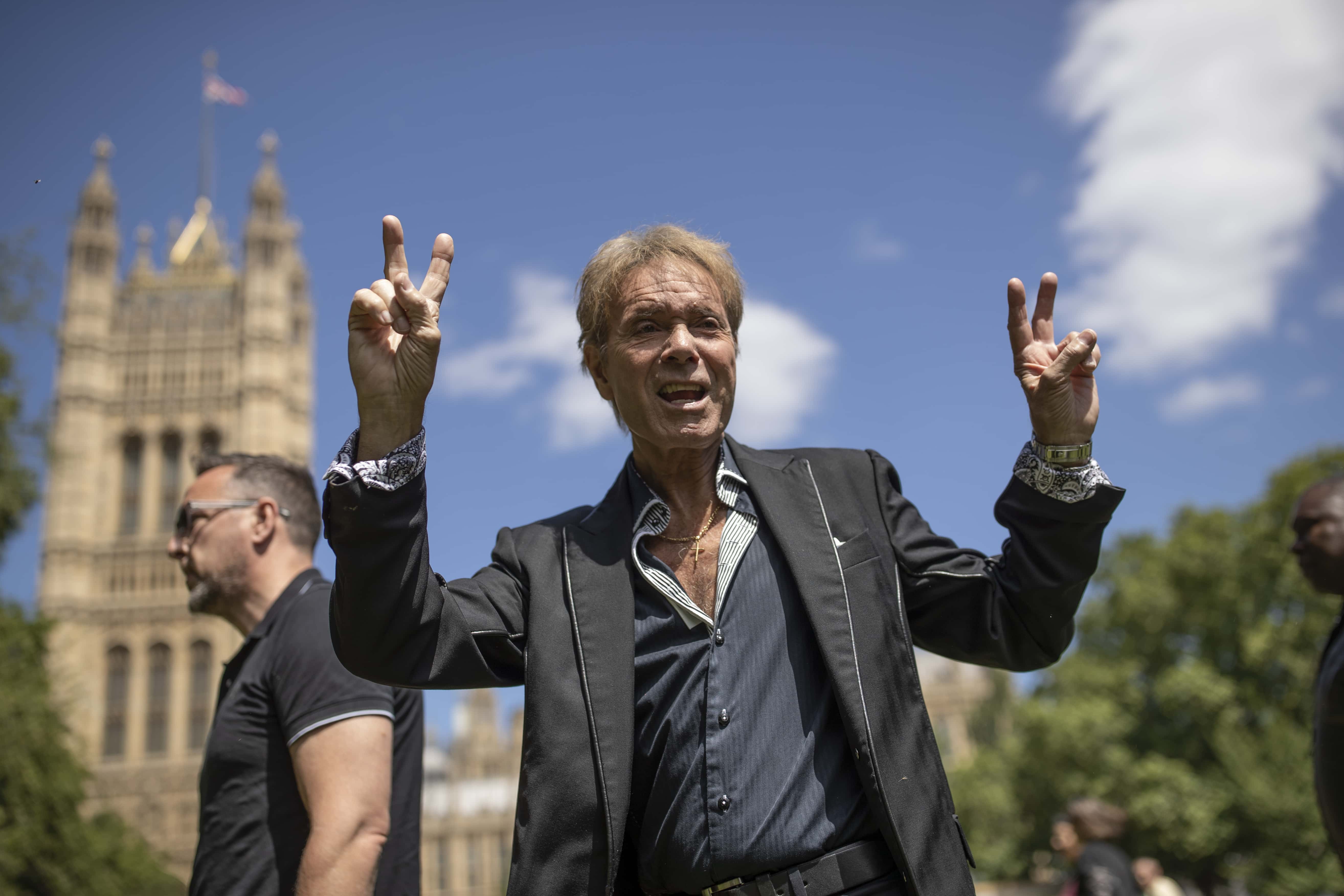 Sir Cliff Richard gestures to fans after speaking to the to the media in Victoria Gardens next to the Houses of Parliament on July 1, 2019 in London, England. Singer Sir Cliff Richard was falsely accused of historical sex offences and now is lending his support to a change in the law to give anonymity to those who are accused of sexual offences until they are charged.