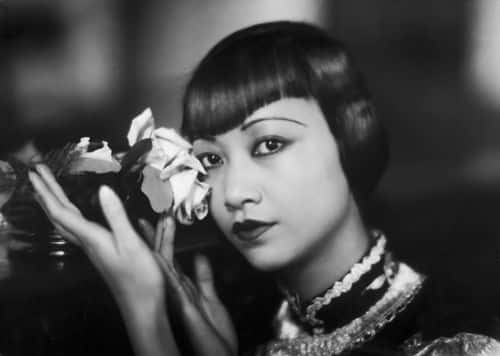 American film star, Anna May Wong (1905 - 1961) poses with a cut rose.