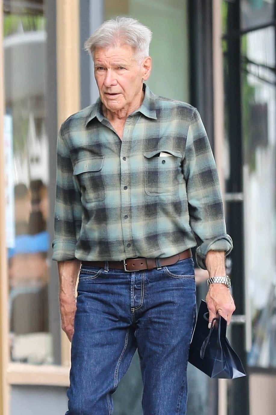 Sporting his signature casual-cool look, he paired blue jeans with a stylish plaid button-down shirt and brown leather boots (Backgrid)