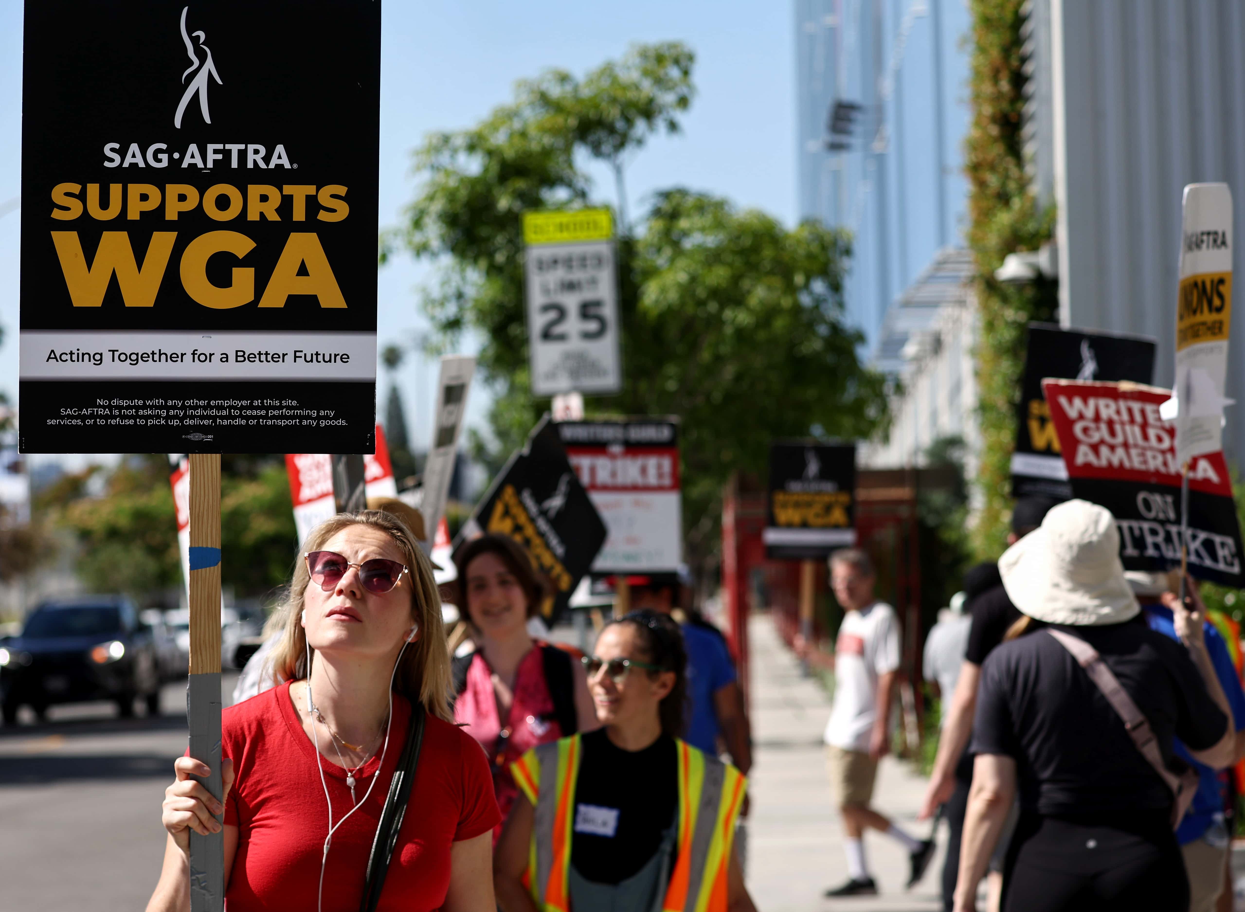 LOS ANGELES, CALIFORNIA - JULY 13: A sign reads 'SAG-AFTRA Supports WGA' as SAG-AFTRA members walk the picket line in solidarity with striking WGA (Writers Guild of America) workers outside Netflix offices on July 13, 2023 in Los Angeles, California. Members of SAG-AFTRA, Hollywood’s largest union which represents actors and other media professionals, will likely go on strike after a midnight deadline over contract negotiations with studios expired. The strike could shut down Hollywood productions completely with writers in the third month of their strike against Hollywood studios. (Photo by Mario Tama/Getty Images)