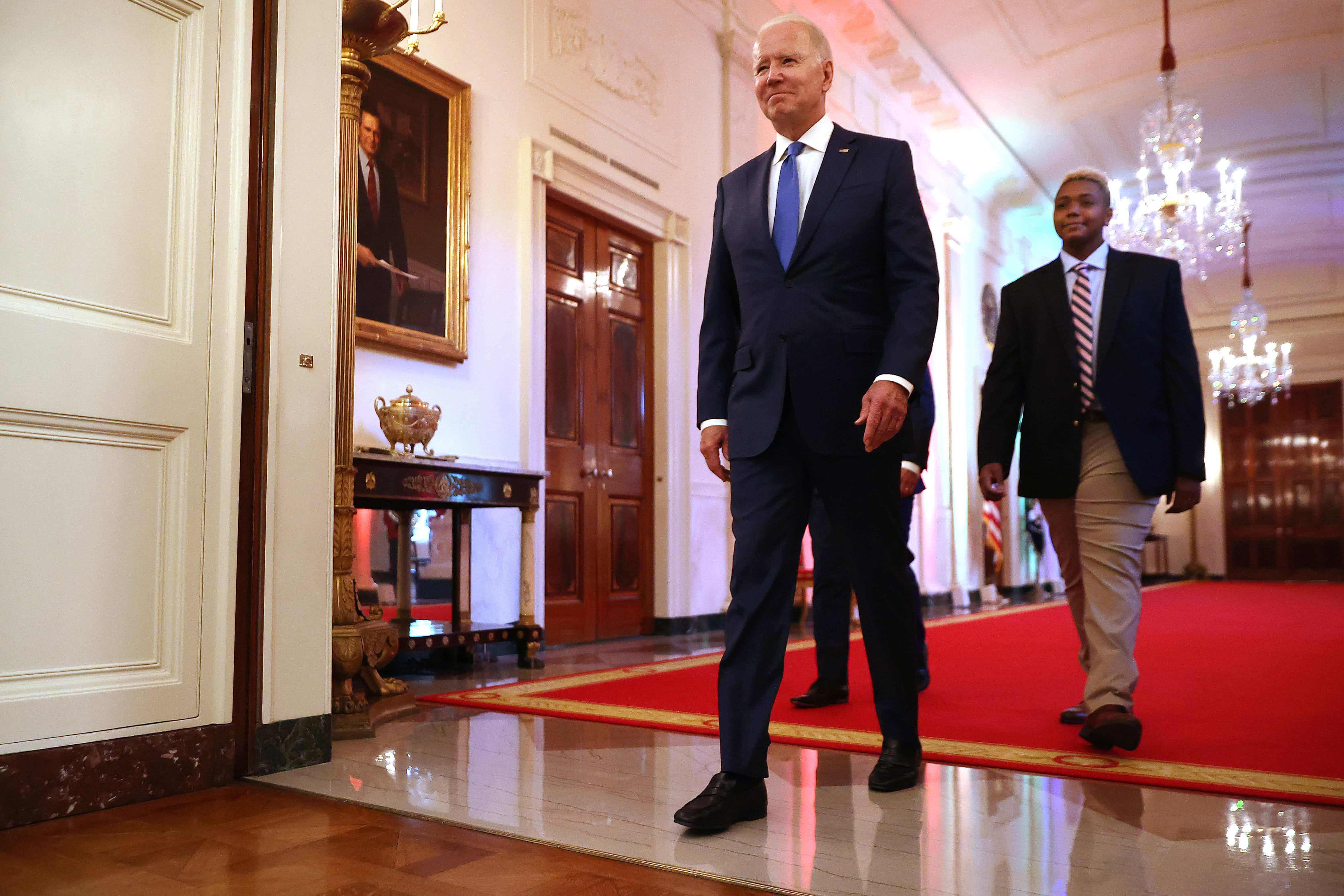 U.S. President Joe Biden (L) and Ashton Mota walk into the East Room for an event commemorating LGBTQ+ Pride Month at the White House on June 25, 2021 in Washington, DC. Sixteen years old and transgender, Mota is a Human Rights Campaign youth ambassador from Lowell, Massachusetts. (Photo by Chip Somodevilla/Getty Images)