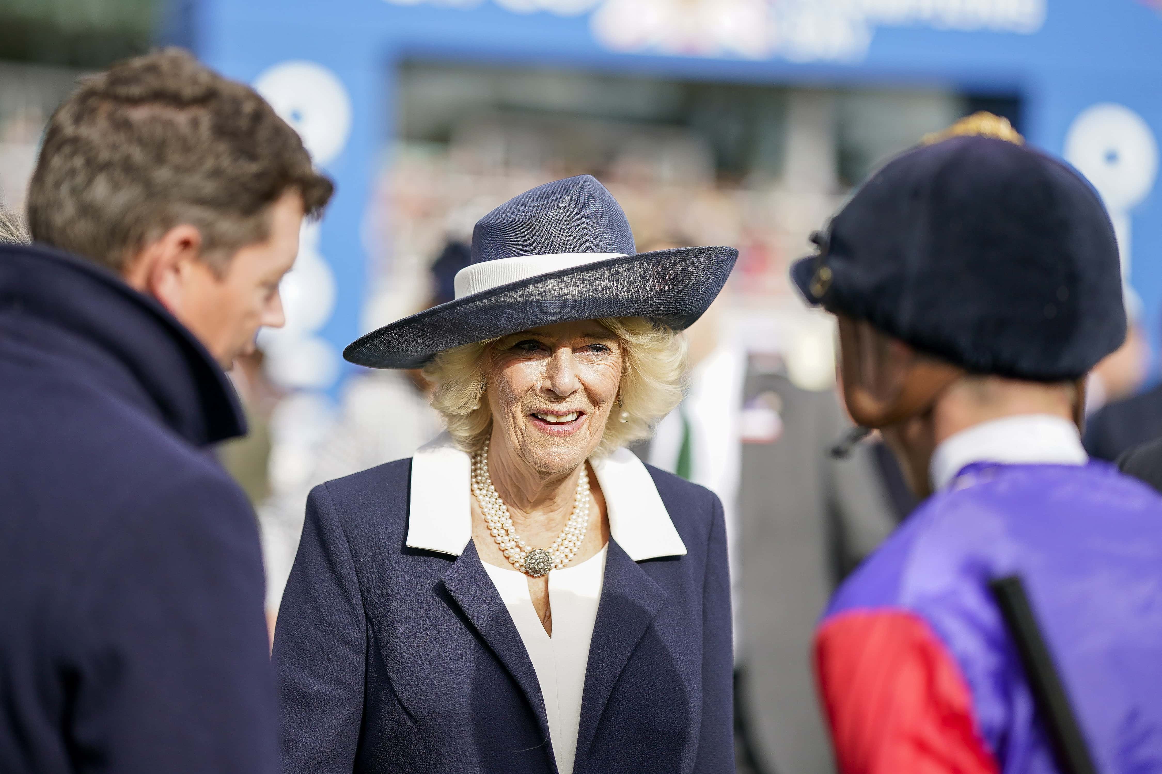Camilla, Queen Consort chats with David Probert (R) and Andrew Balding in the parade ring at Ascot Racecourse on October 15, 2022 in Ascot, England.