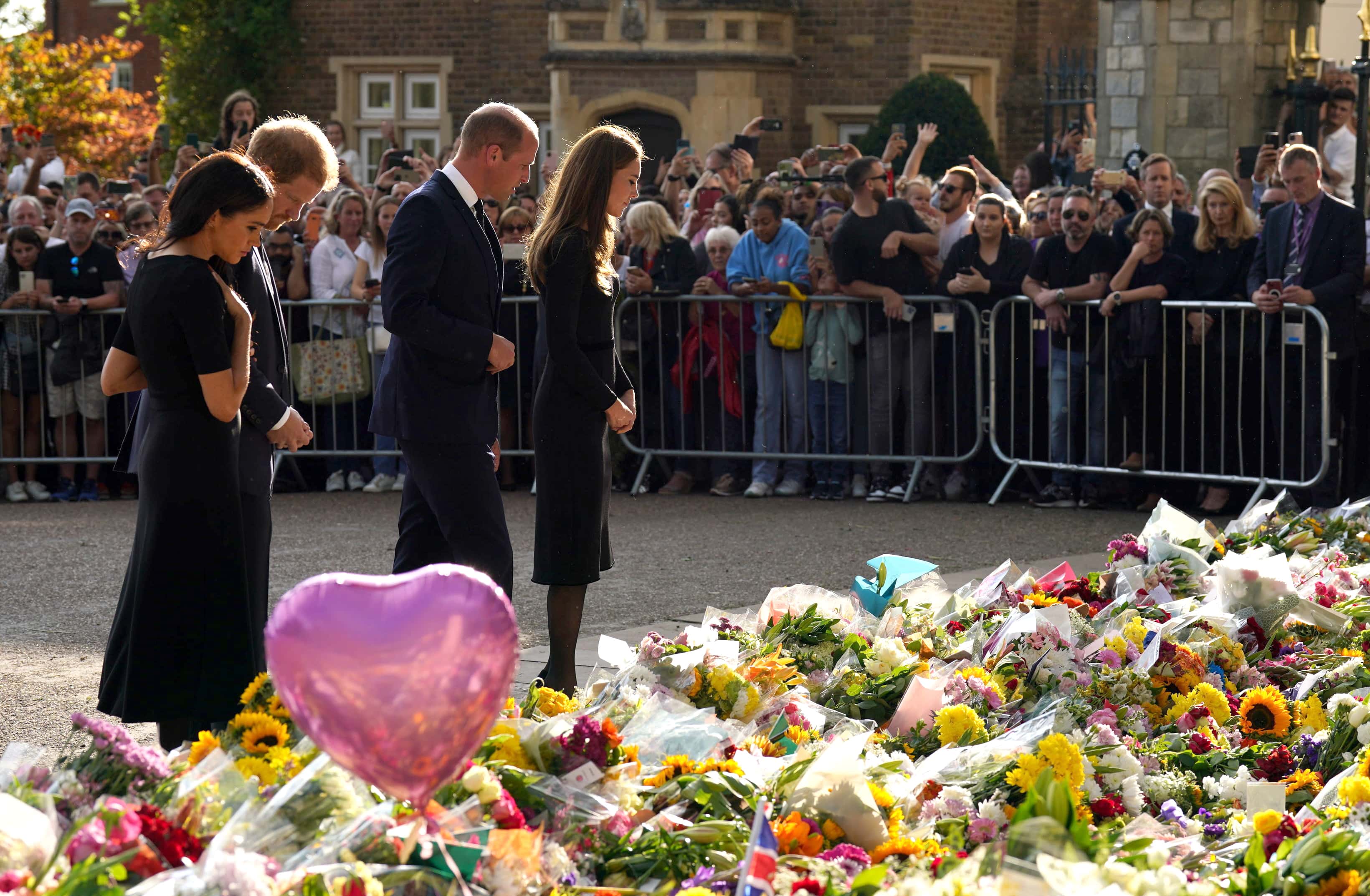 Prince Harry, Duke of Sussex, Meghan, Duchess of Sussex, Catherine, Princess of Wales and Prince William, Prince of Wales view floral tributes left at Windsor Castle on September 10, 2022 in Windsor, England. Crowds have gathered and tributes left at the gates of Windsor Castle to Queen Elizabeth II, who died at Balmoral Castle on 8 September, 2022.