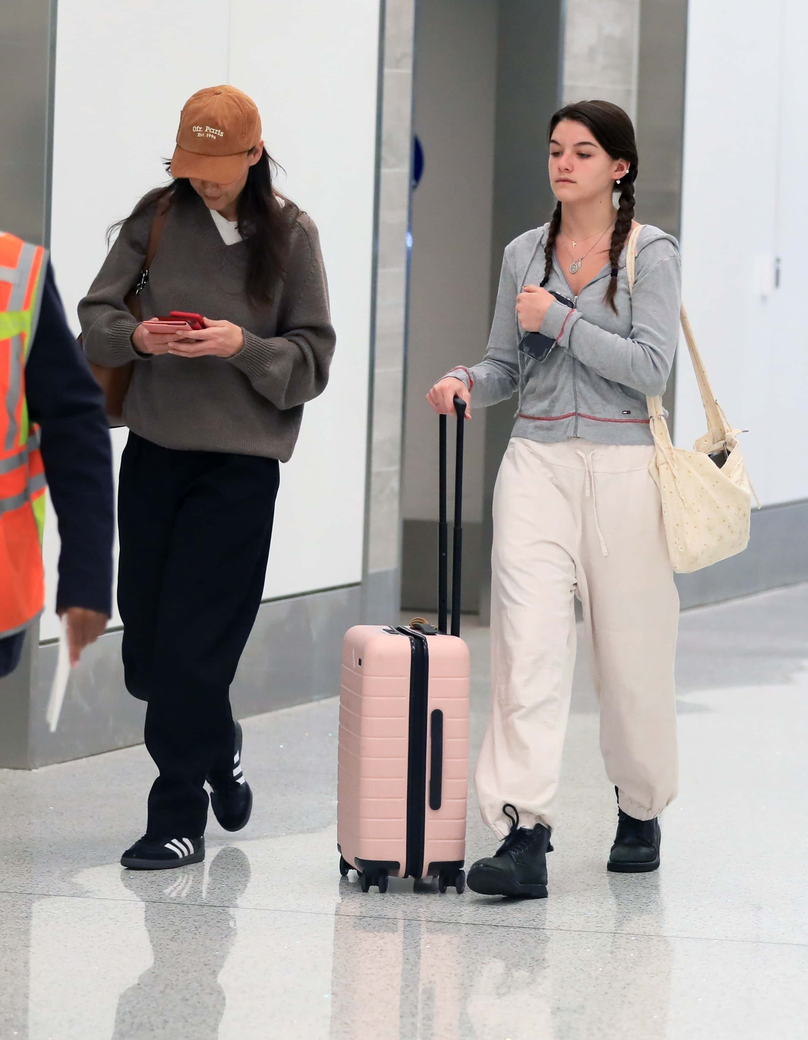 As the duo prepared to board their flight, the Alone Together actress' teenager, 17, strolled alongside her famous mother's side while rolling a light pink suitcase (backgrid)