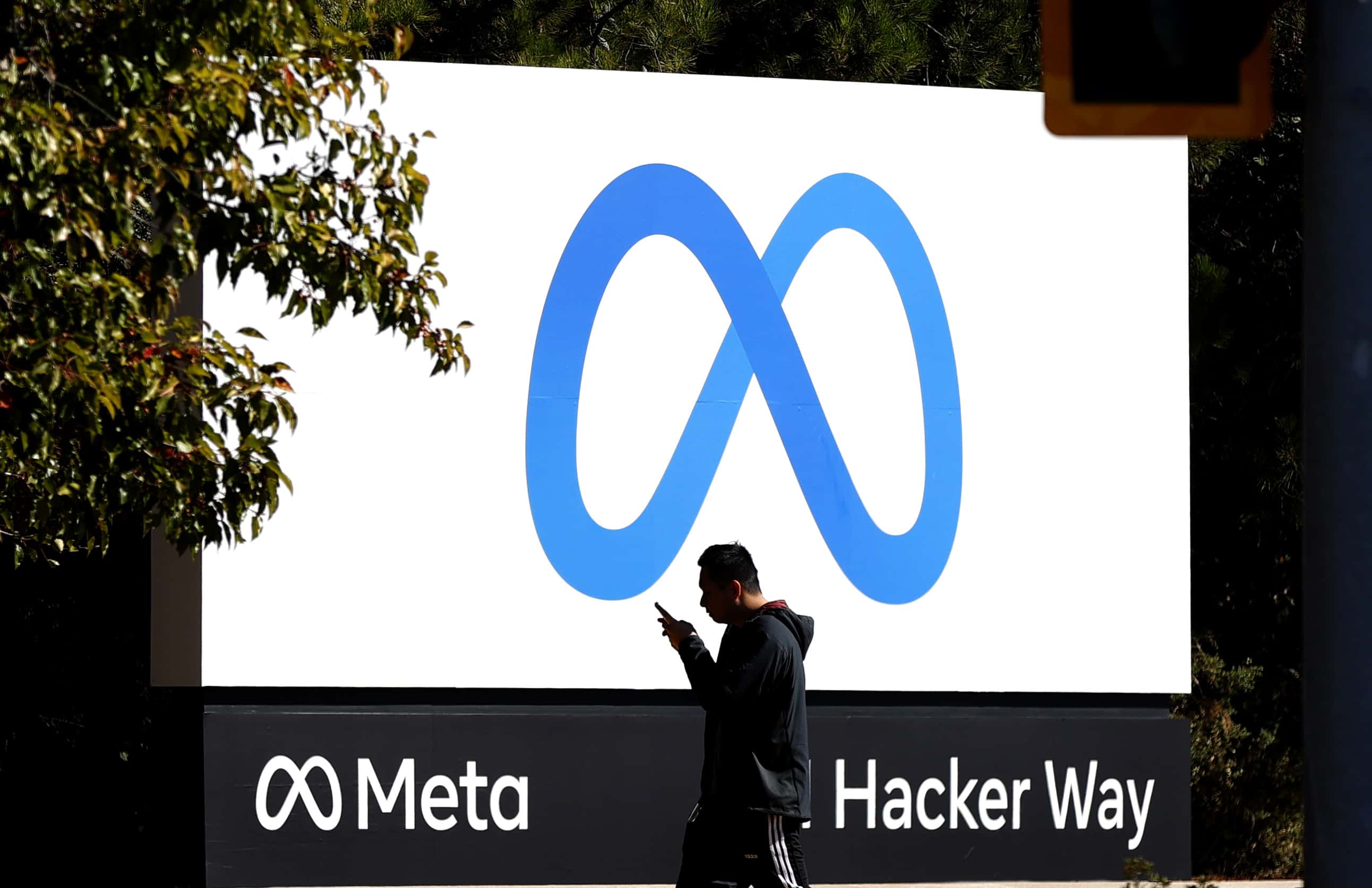 A pedestrian walks in front of a new logo and the name 'Meta' on the sign in front of Facebook headquarters on October 28, 2021 in Menlo Park, California. A new name and logo were unveiled at Facebook headquarters after a much anticipated name change for the social media platform.