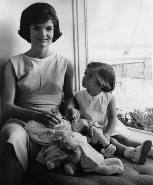 Jacqueline Kennedy (1929 - 1994), wife of US President John F Kennedy,  and daughter Caroline relax together at home.