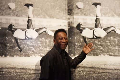 Pele poses in front of Russell Young - Bicycle Kick as he launches Art, Life, Football at Halcyon Gallery on September 22, 2015 in London, England.