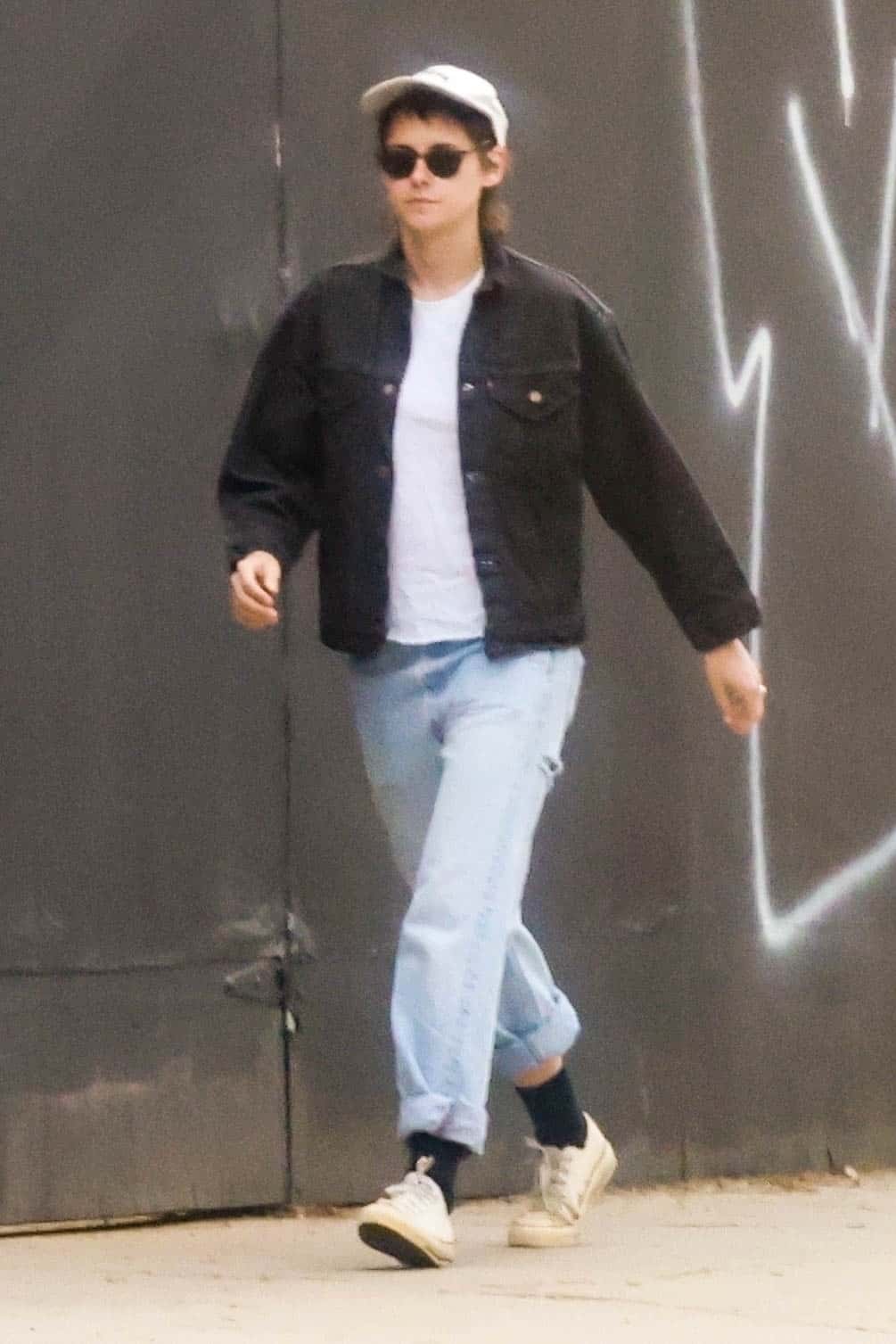 Popping a baseball cap over her dark brown mullet, Kristen rounded off the ensemble with a pair of simple white sneakers over black socks (Backgrid)