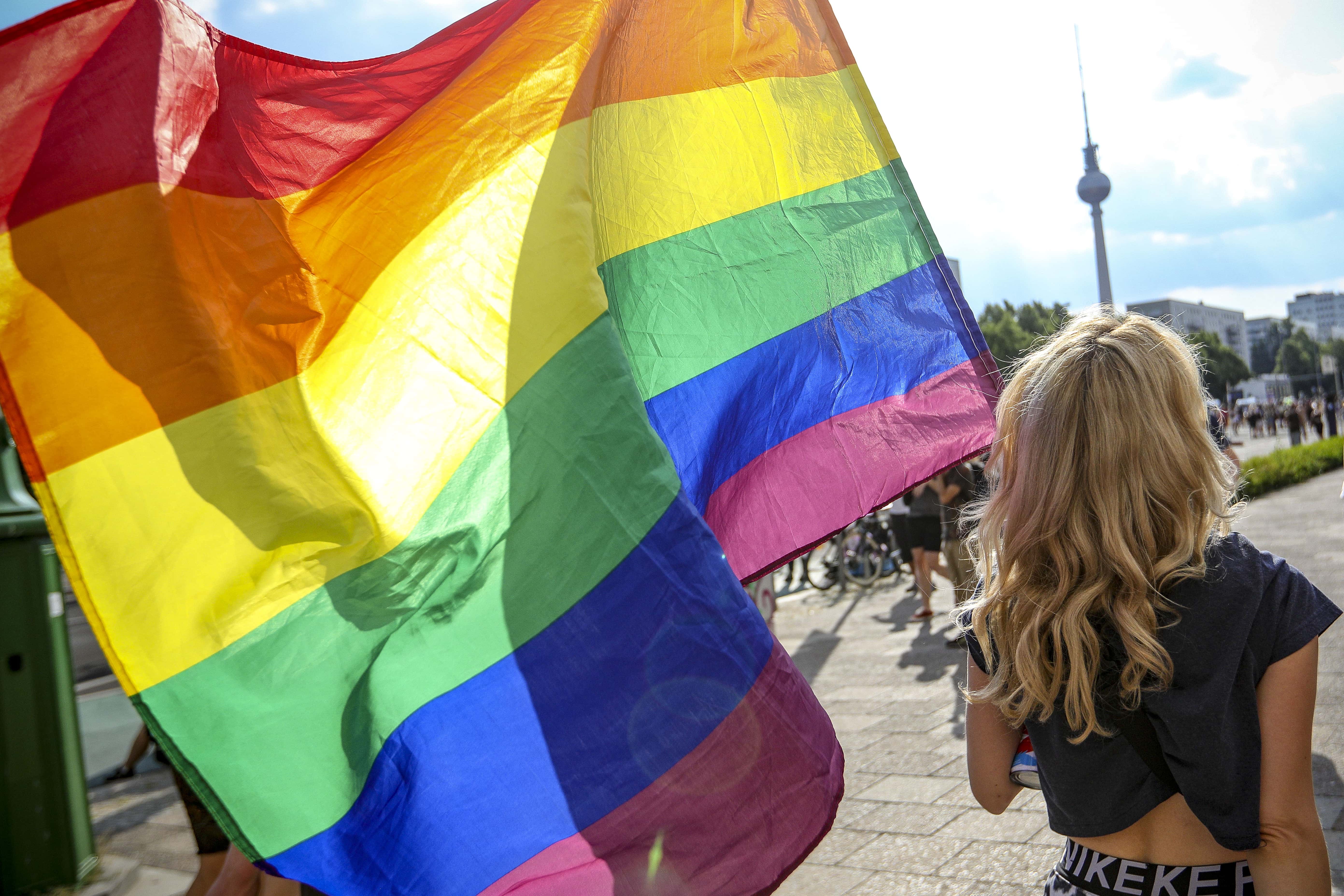 A participant holds the rainbow pride flag in the Queerschutz Now! (Queer Protection Now!) march through Karl-Marx-Allee street in commemoration and celebration of Christopher Street Day on June 26, 2021 in Berlin, Germany. A variety of gay pride marches and gatherings are taking place across the city today, each with its own political or thematic emphasis. The marches are taking place close to the 52nd anniversary of the 1969 riots following a police raid at The Stonewall Inn in New York City that ignited the gay rights movement.