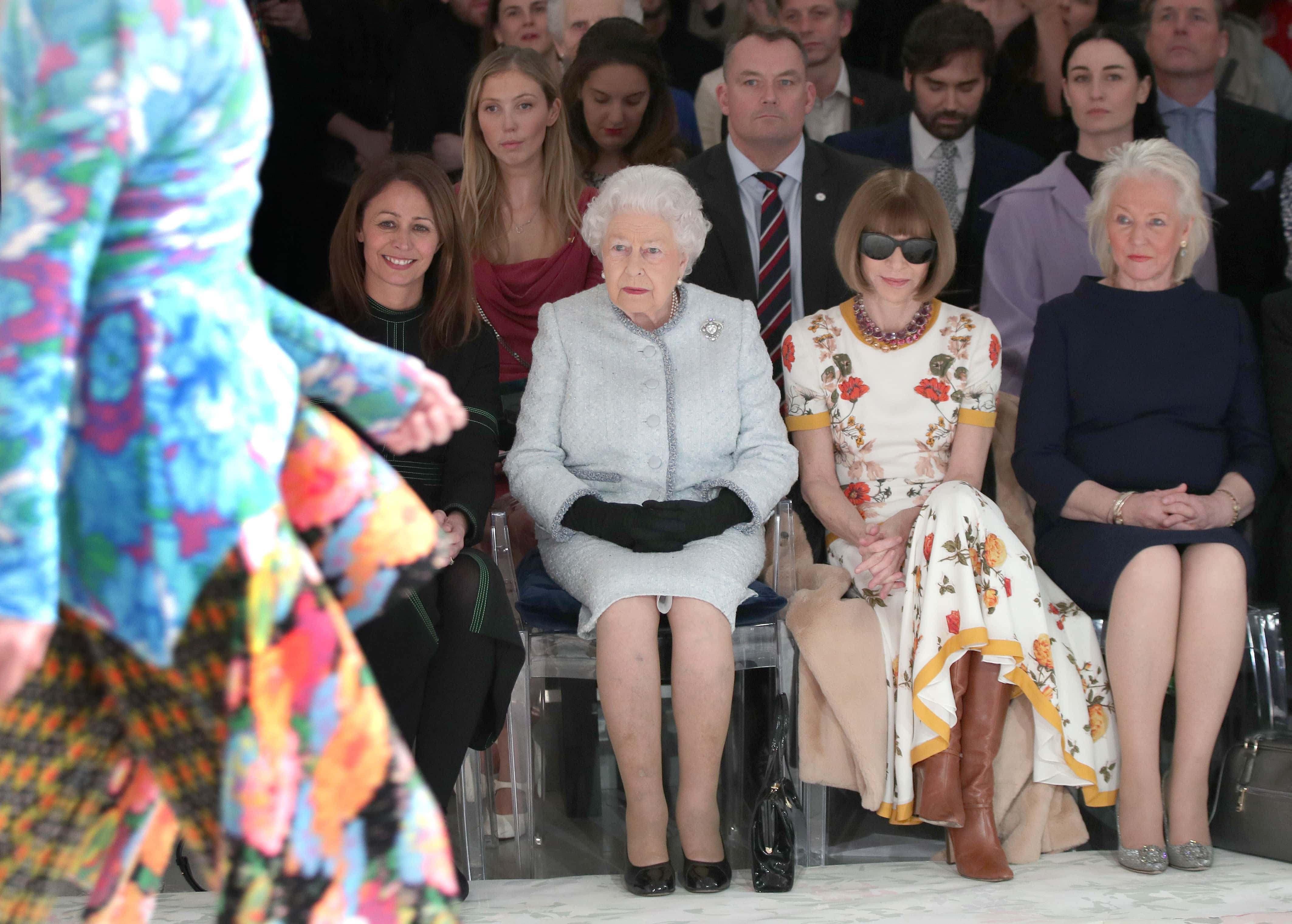 Queen Elizabeth II sits with Anna Wintour, Caroline Rush (L), chief executive of the British Fashion Council (BFC) and royal dressmaker Angela Kelly (R) as they view Richard Quinn's runway show before presenting him with the inaugural Queen Elizabeth II Award for British Design as she visits London Fashion Week's BFC Show Space on February 20, 2018 in London, United Kingdom.