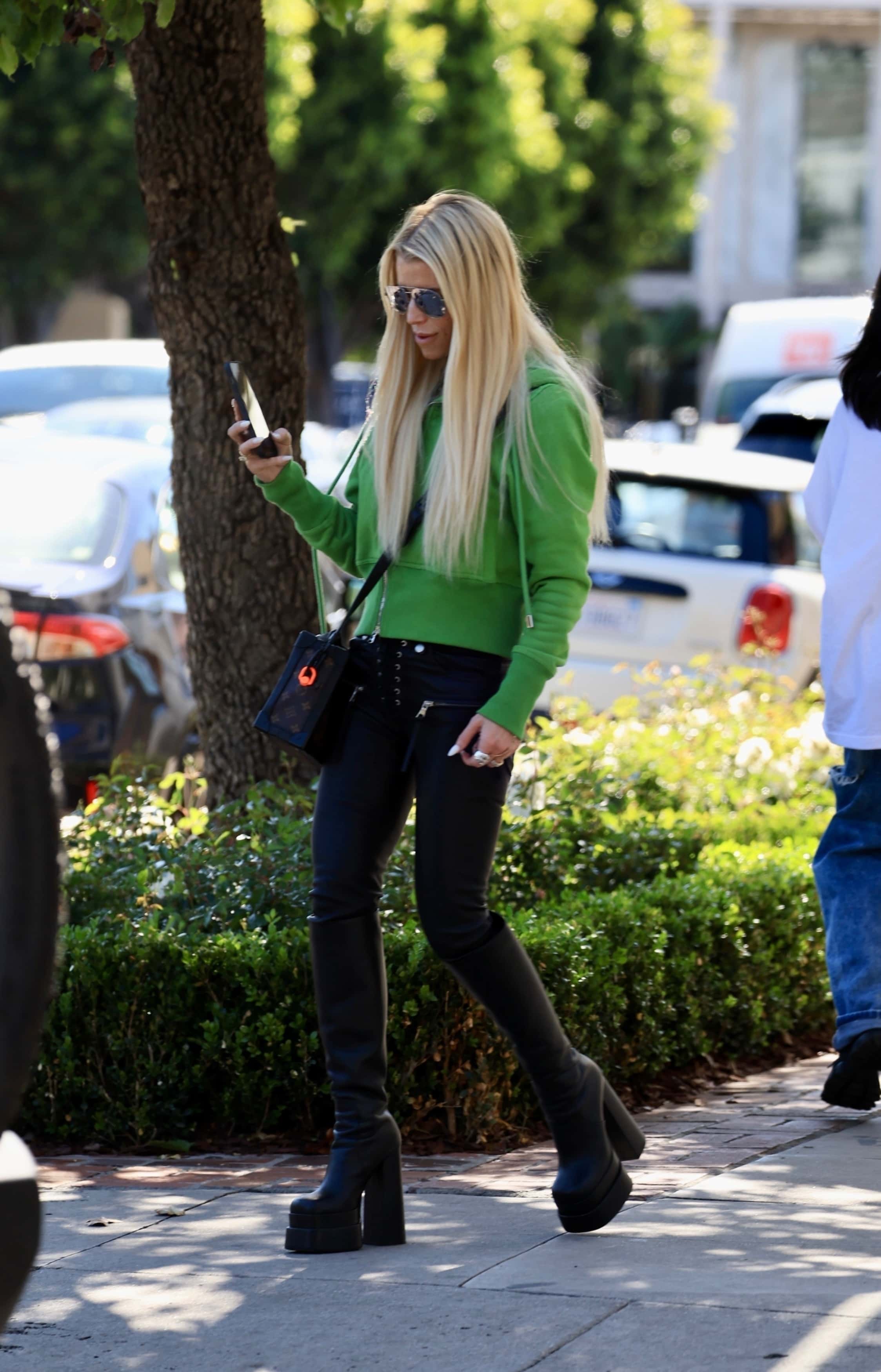 The entrepreneur wore chrome aviator sunglasses and hid her petite frame beneath a green hooded sweatshirt (Backgrid)

