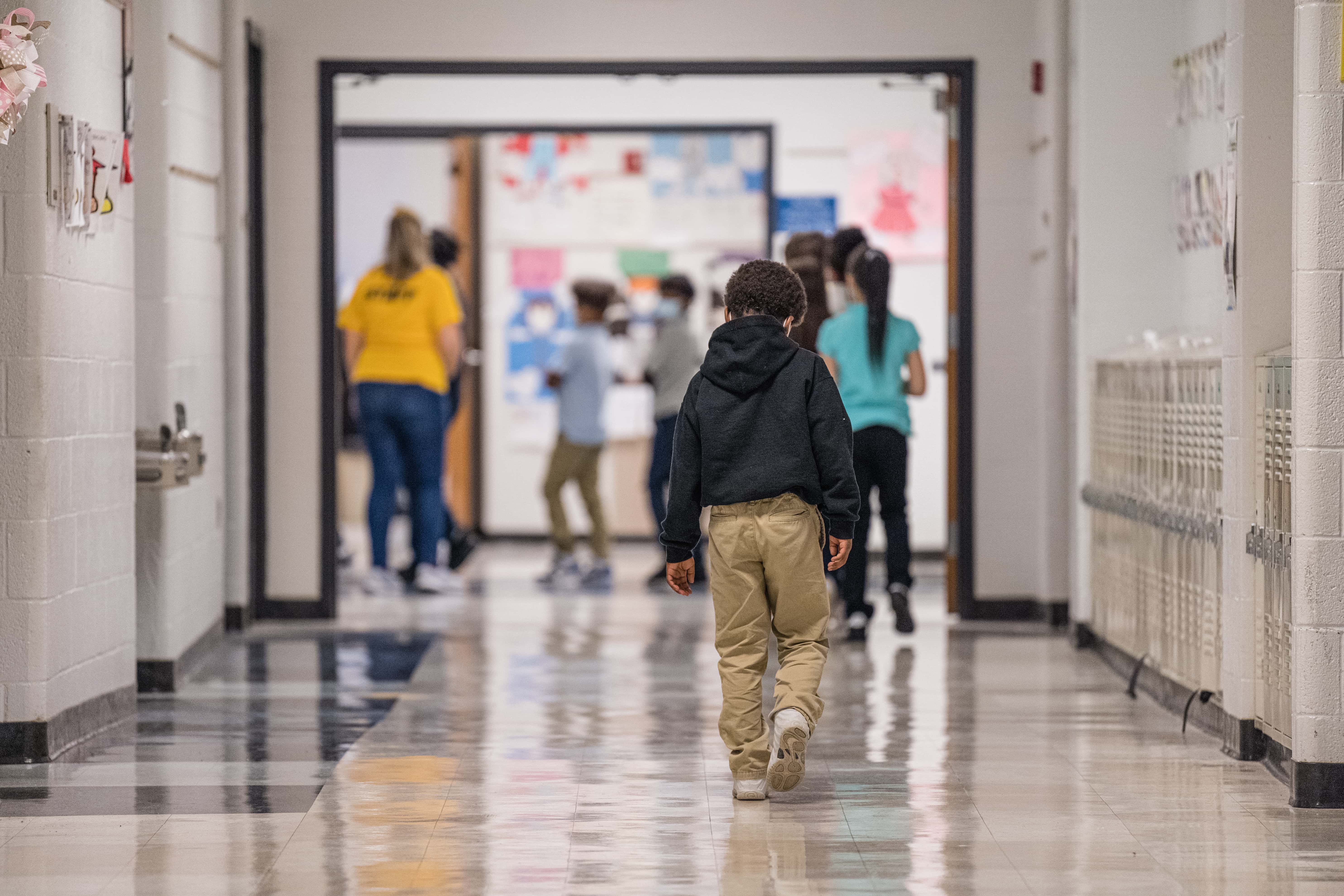 A young boy walks down a hallway  at Carter Traditional Elementary School on January 24, 2022 in Louisville, Kentucky. Students in the district are returning to in-person class after two weeks of Non-Traditional Instruction (NTI) due to staffing issues caused by a surge of the COVID-19 omicron variant.
