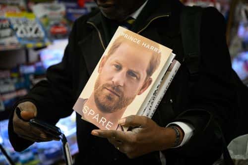 A man prepares to take a selfie as he holds copies of