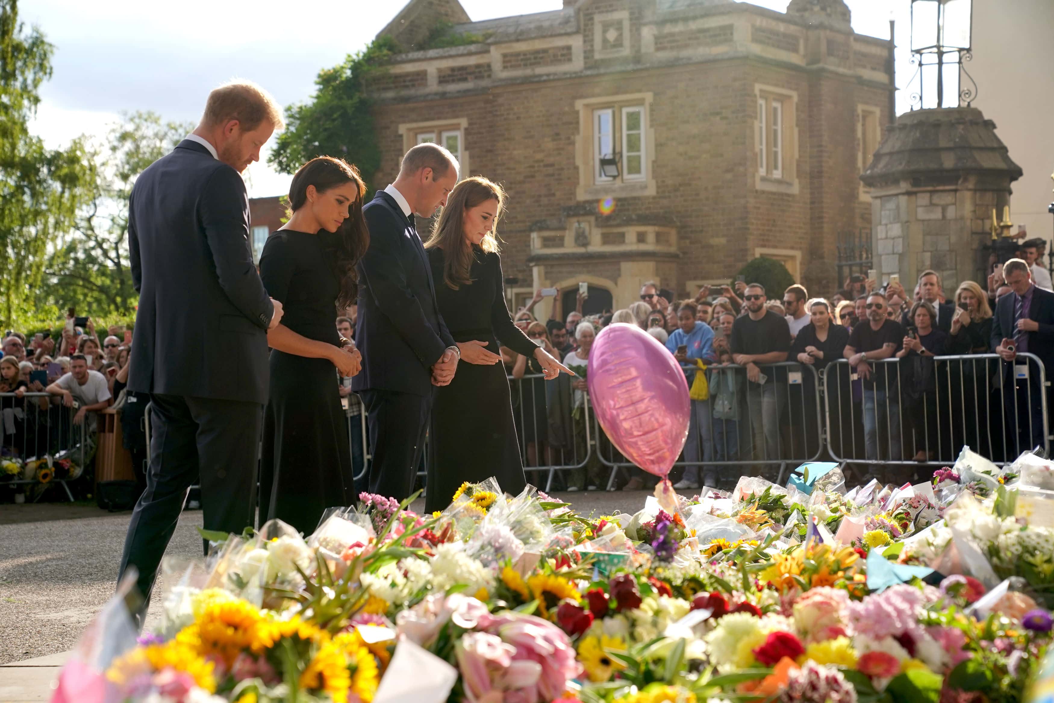 Prince Harry, Duke of Sussex, Meghan, Duchess of Sussex, Catherine, Princess of Wales and Prince William, Prince of Wales view floral tributes left at Windsor Castle on September 10, 2022 in Windsor, England. Crowds have gathered and tributes left at the gates of Windsor Castle to Queen Elizabeth II, who died at Balmoral Castle on 8 September, 2022.
