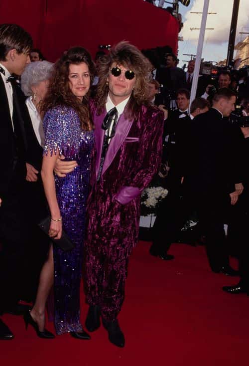 American singer, songwriter and guitarist Jon Bon Jovi, wearing a purple velvet suit, and his wife, Dorothea Hurley attend the 63rd Academy Awards, held at the Shrine Auditorium in Los Angeles, California, 25th March 1991. (Photo by Vinnie Zuffante/Michael Ochs Archives/Getty Images)