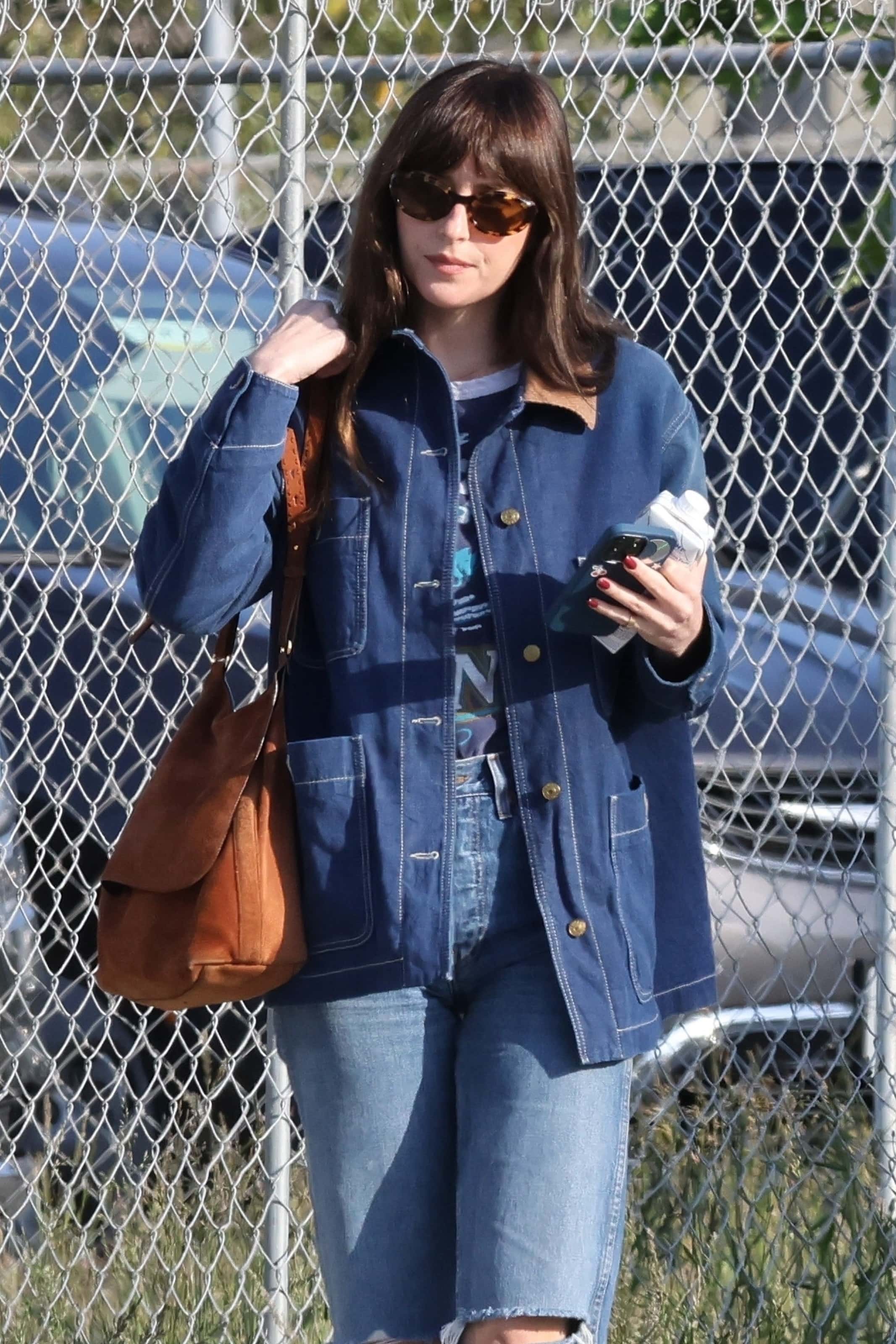 Dakota wore a Gucci jean jacket and denim trousers, stylishly ripped at the knee and accessorized with a tan side bag and shades (Backgrid)