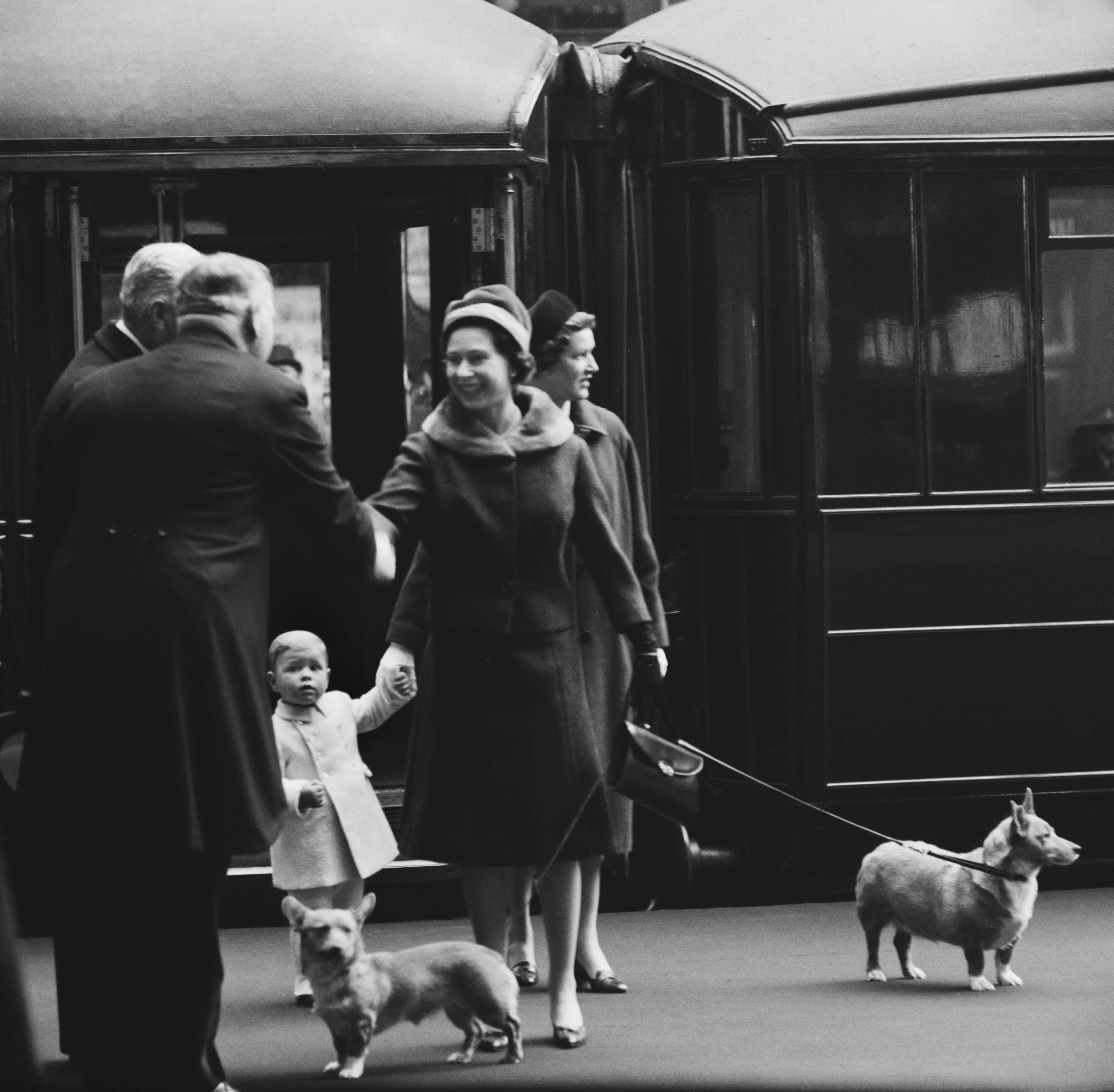 British Royal Queen Elizabeth II is greeted by an unspecified person, with Prince Andrew and his nanny, Mabel Anderson, in the background along with two of the Queen's corgis, on their arrival at Liverpool Street Station in London, England, 2nd February 1962. The Royal Family are returning to London following their stay at the Sandringham Estate. (Photo by Evening Standard/Hulton Archive/Getty Images)
