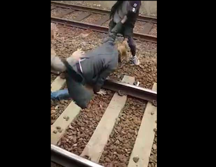 The boy drags the man onto the tracks (Twitter)