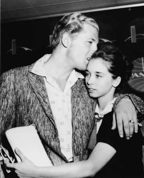 American rock musician Jerry Lee Lewis hugs his second cousin and third wife Myra Brown as they arrive in the airport from London after his tour of England was cancelled, New York, May 28, 1958. (Photo by Hulton Archive/Getty Images)