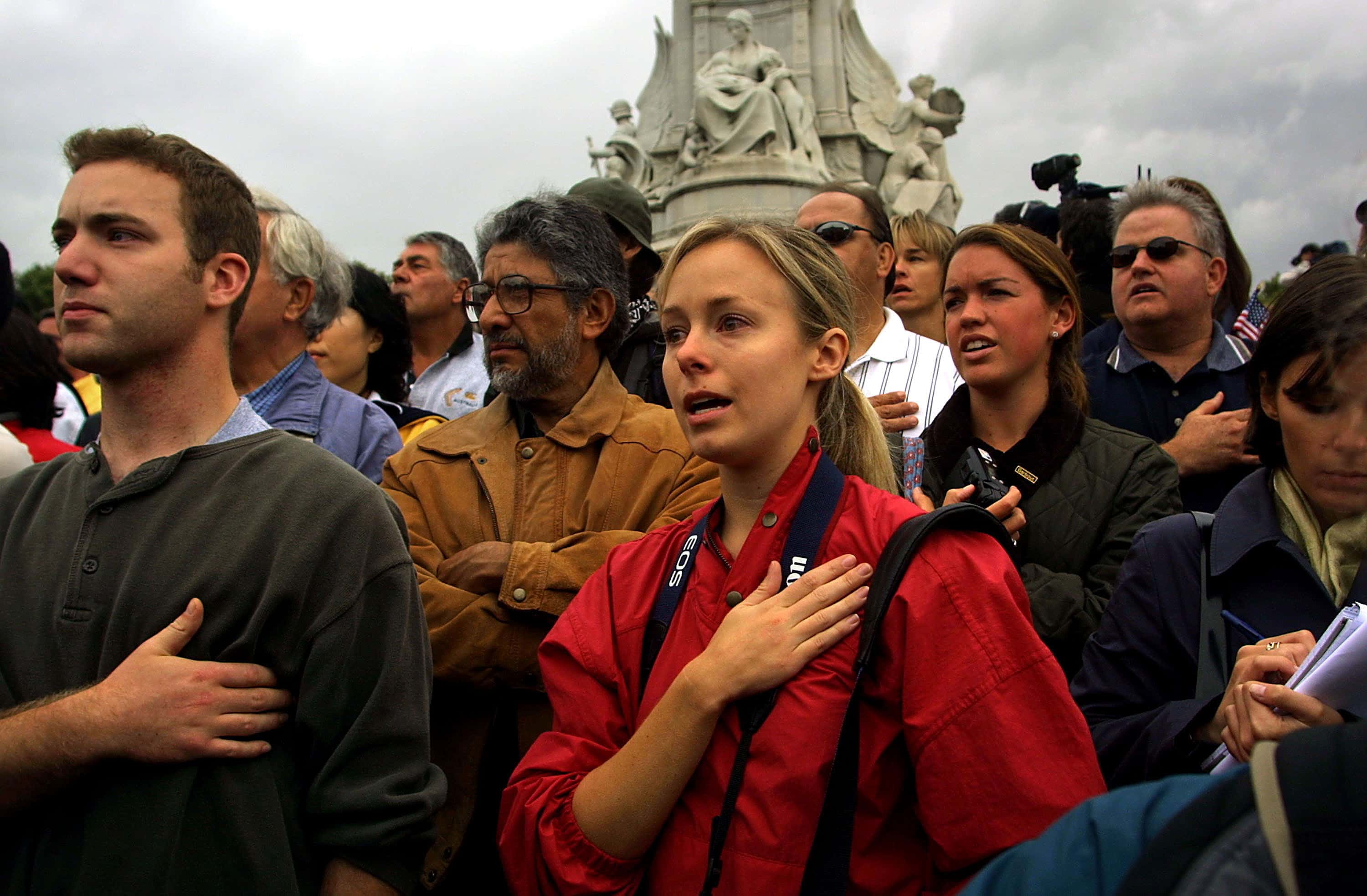Americans sing the U.S. National Anthem September 13, 2001 during a special Changing of the Guard and a minute of silence for victims of the terrorist attacks in the U.S. at the Queen Victoria Monument outside Buckingham Palace in London. (Photo by Sion Touhig/Getty Images)